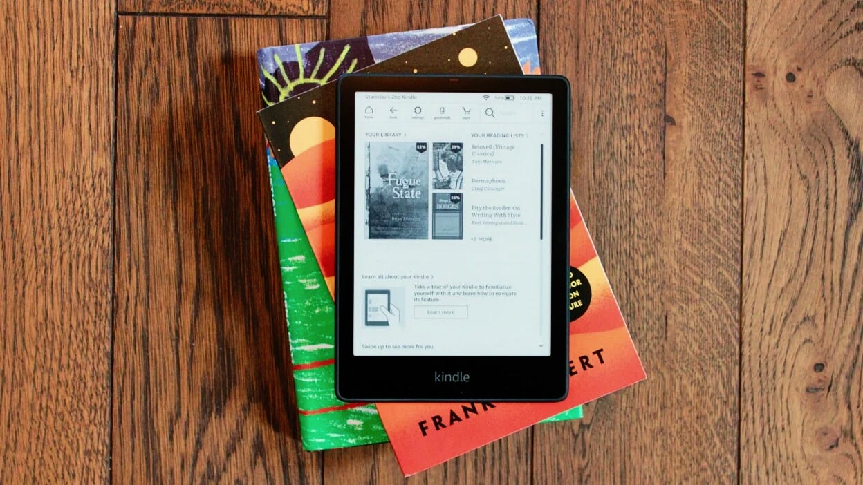 kindle paperwhite signature edition on stack of books on wood floor