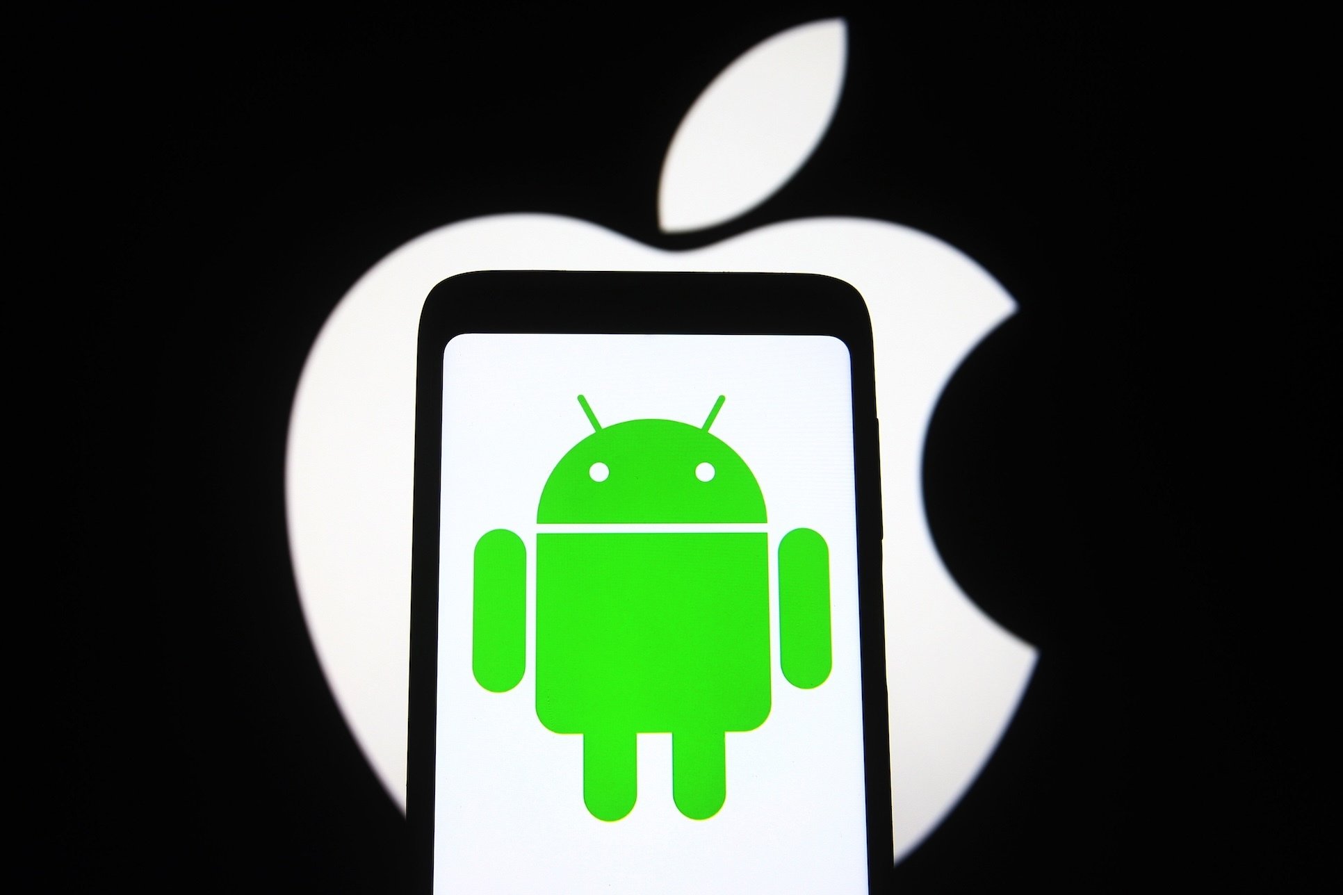 An Android logo on a phone, trapped inside an Apple logo. 