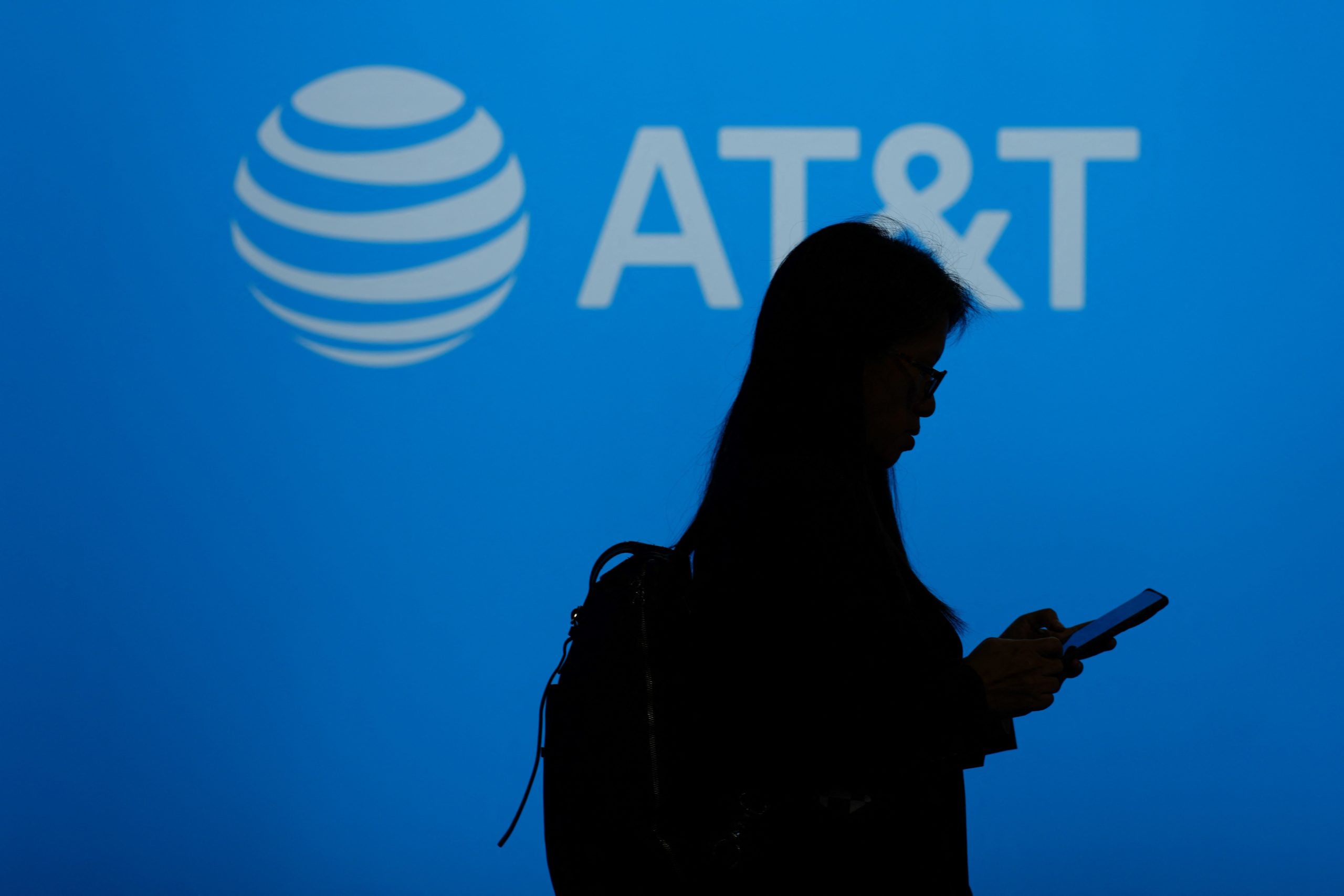 A visitor walks past US multinational telecommunications AT&T logo during the Mobile World Congress (MWC), the telecom industry's biggest annual gathering, in Barcelona on February 26, 2024. The world's biggest mobile phone fair throws open its doors in Barcelona with the sector looking to artificial intelligence to try and reverse declining sales.