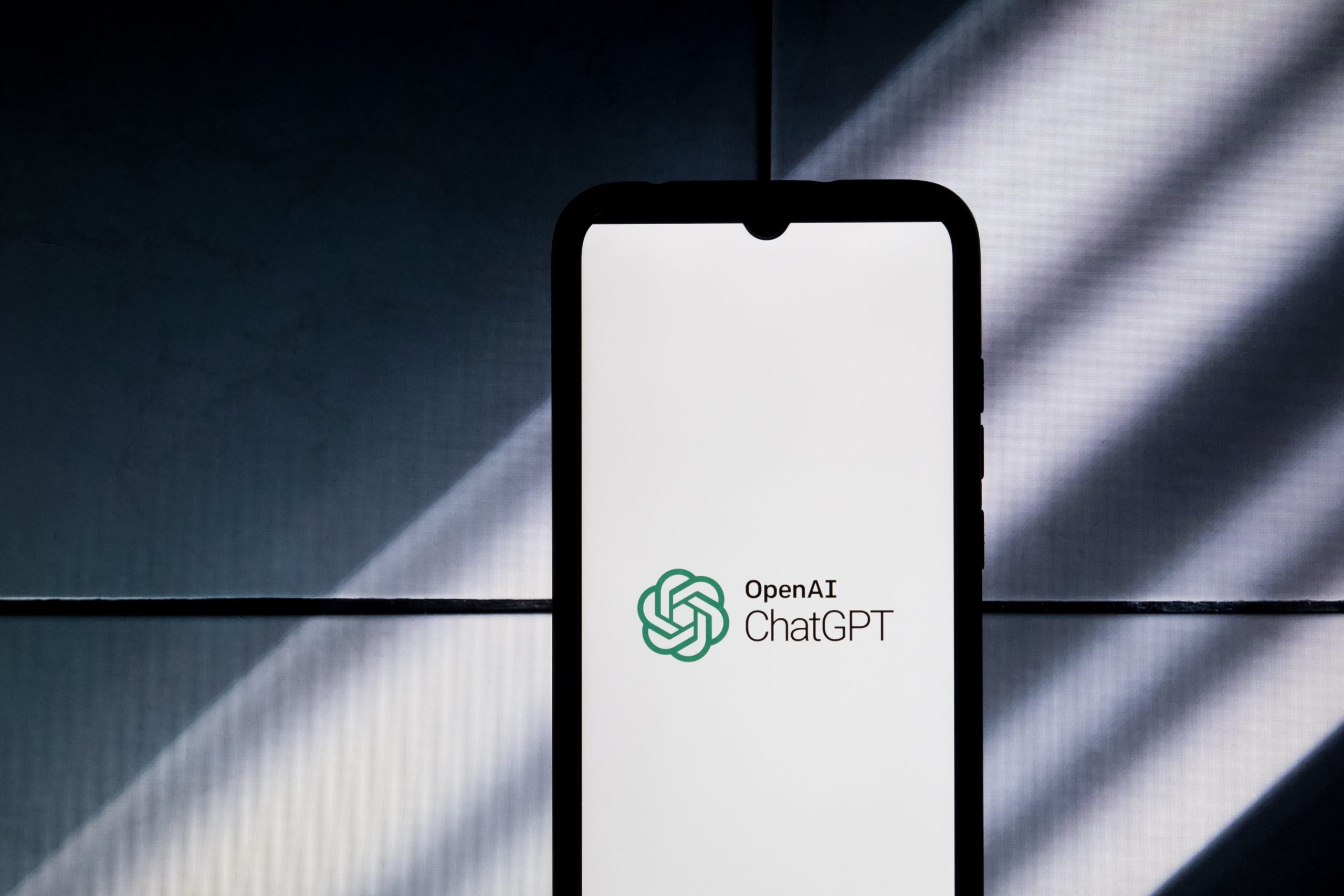 A phone displaying the ChatGPT logo against a shadowed backdrop.