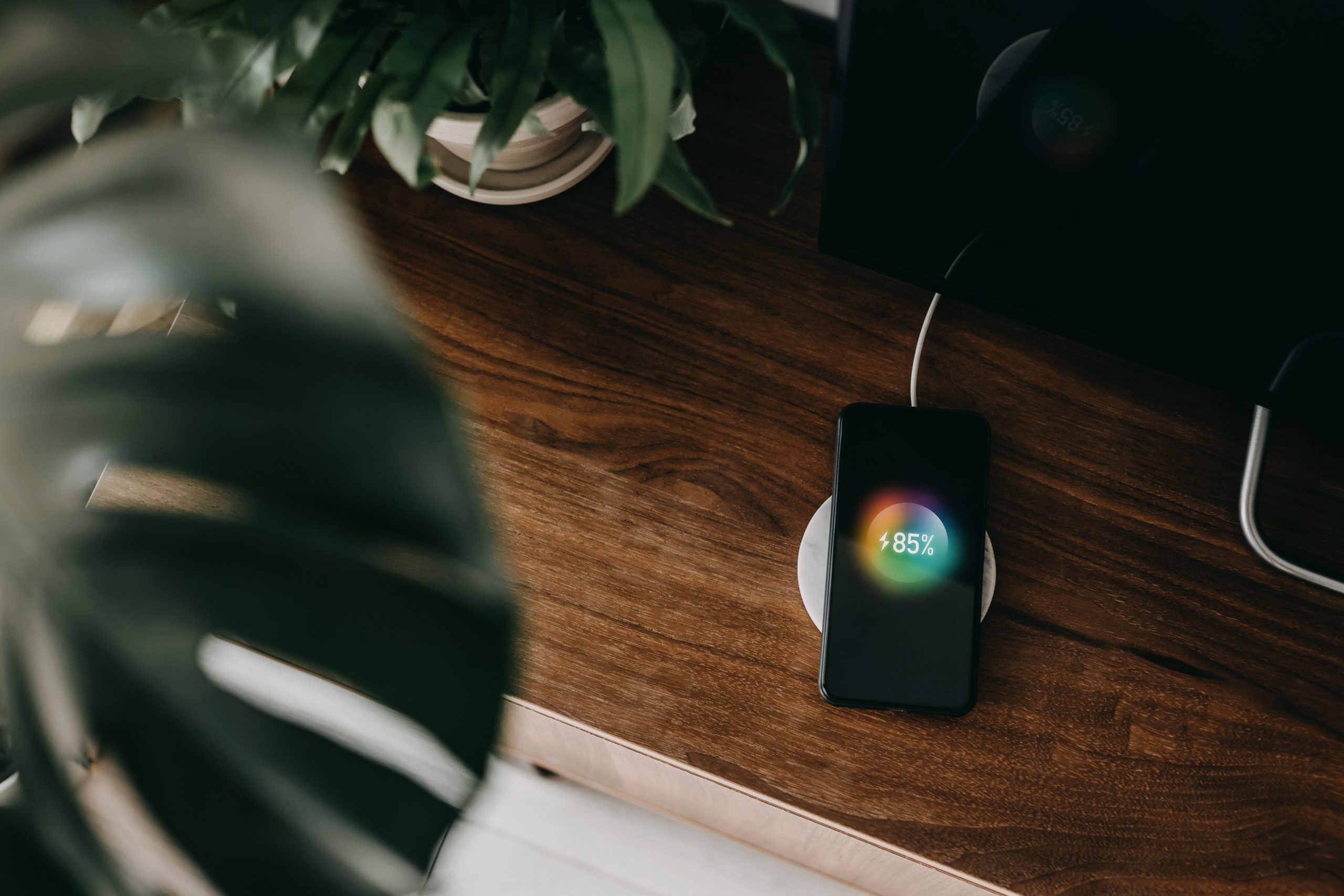 Directly above shot of a smartphone getting charged with wireless charging device on a cabinet in the living room