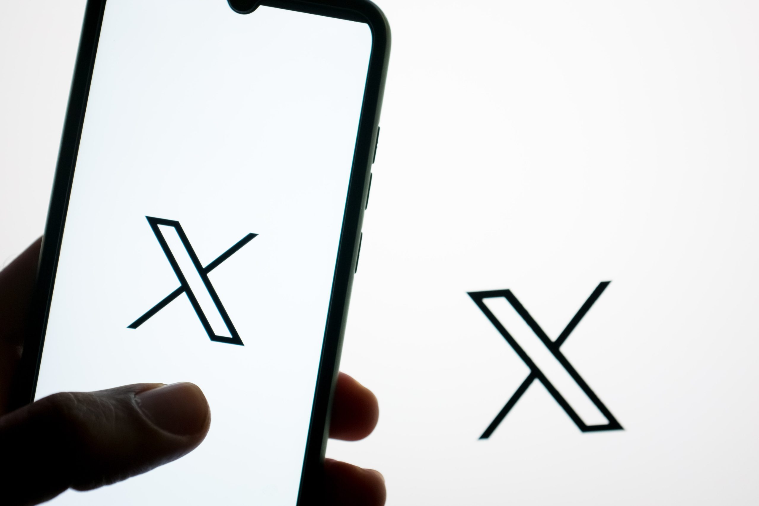 The Twitter logo is being displayed on a smartphone screen and on a computer screen in Athens, Greece, on April 20, 2024.
