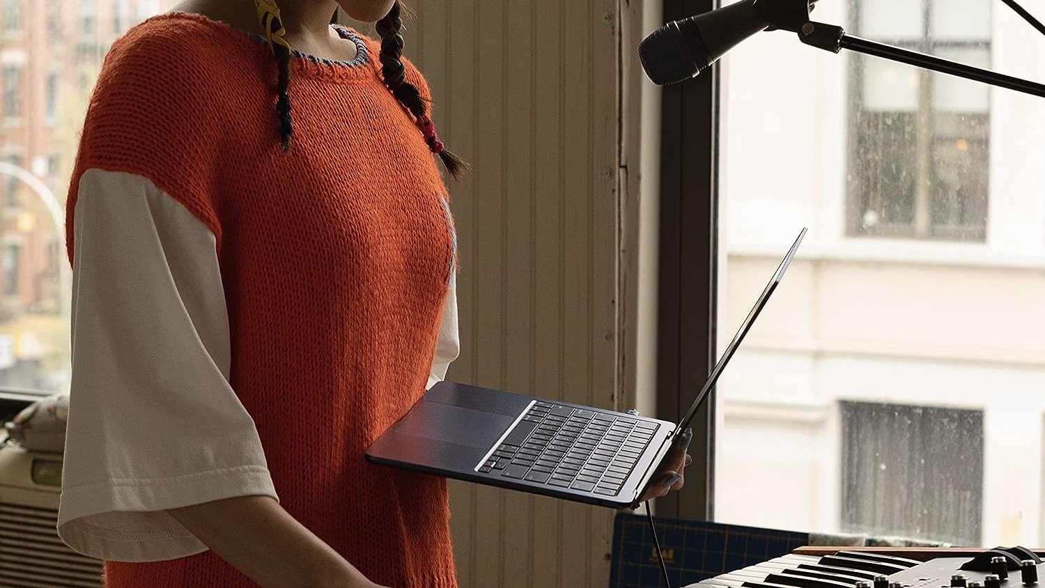 person holding m2 macbook air in front of piano