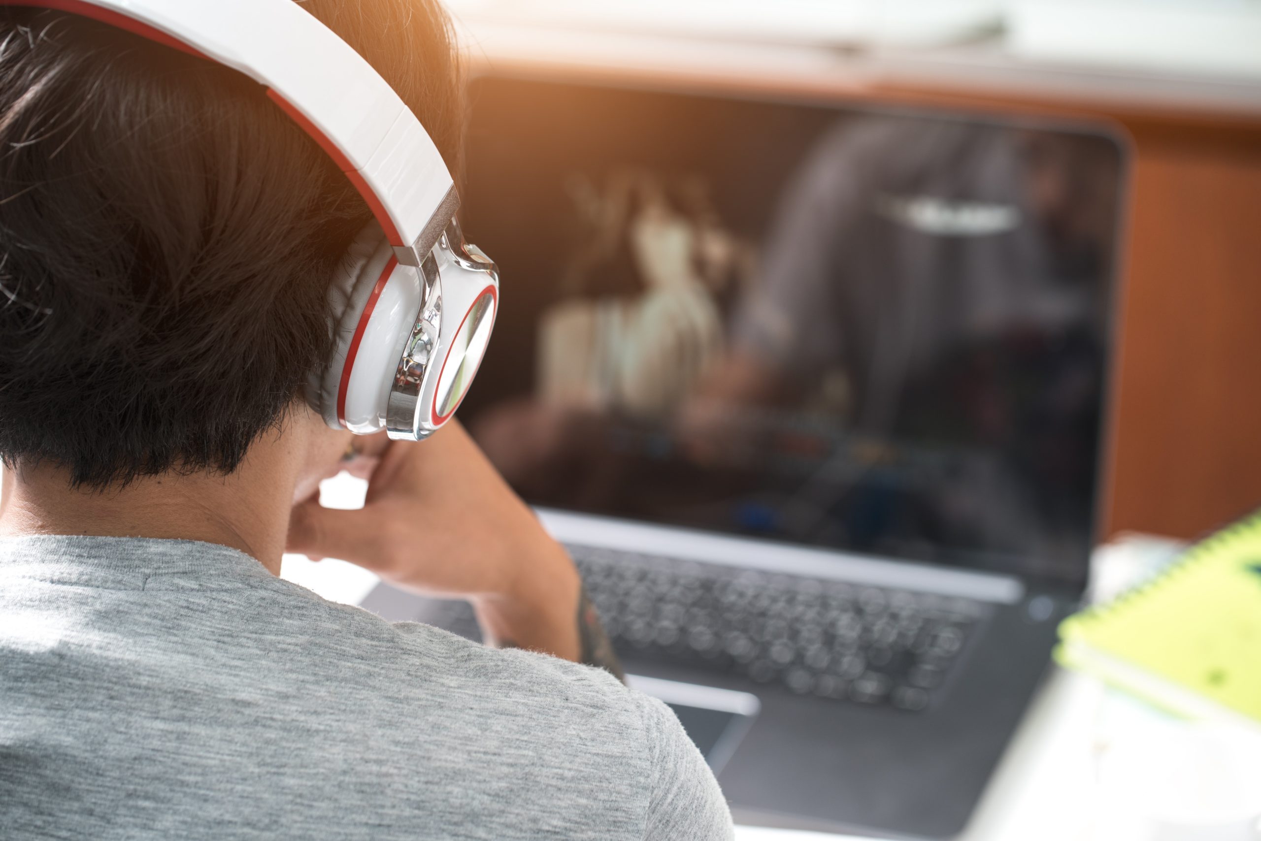 Person in white headphones looks at a computer screen.
