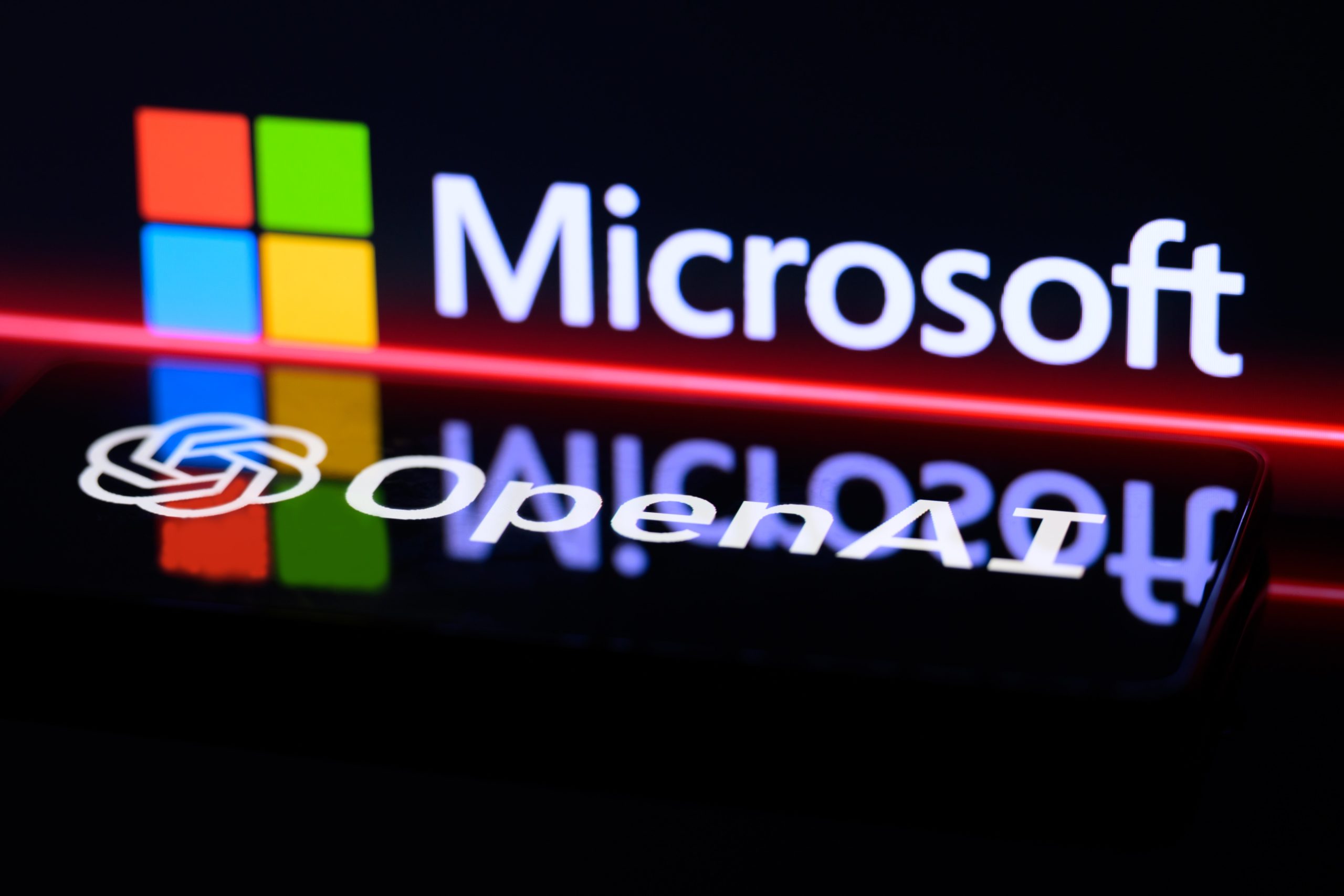 The OpenAI and Microsoft logos projected on a shiny black wall. 