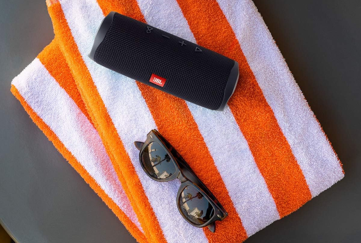 JBL portable speaker on orange and white beach towel 