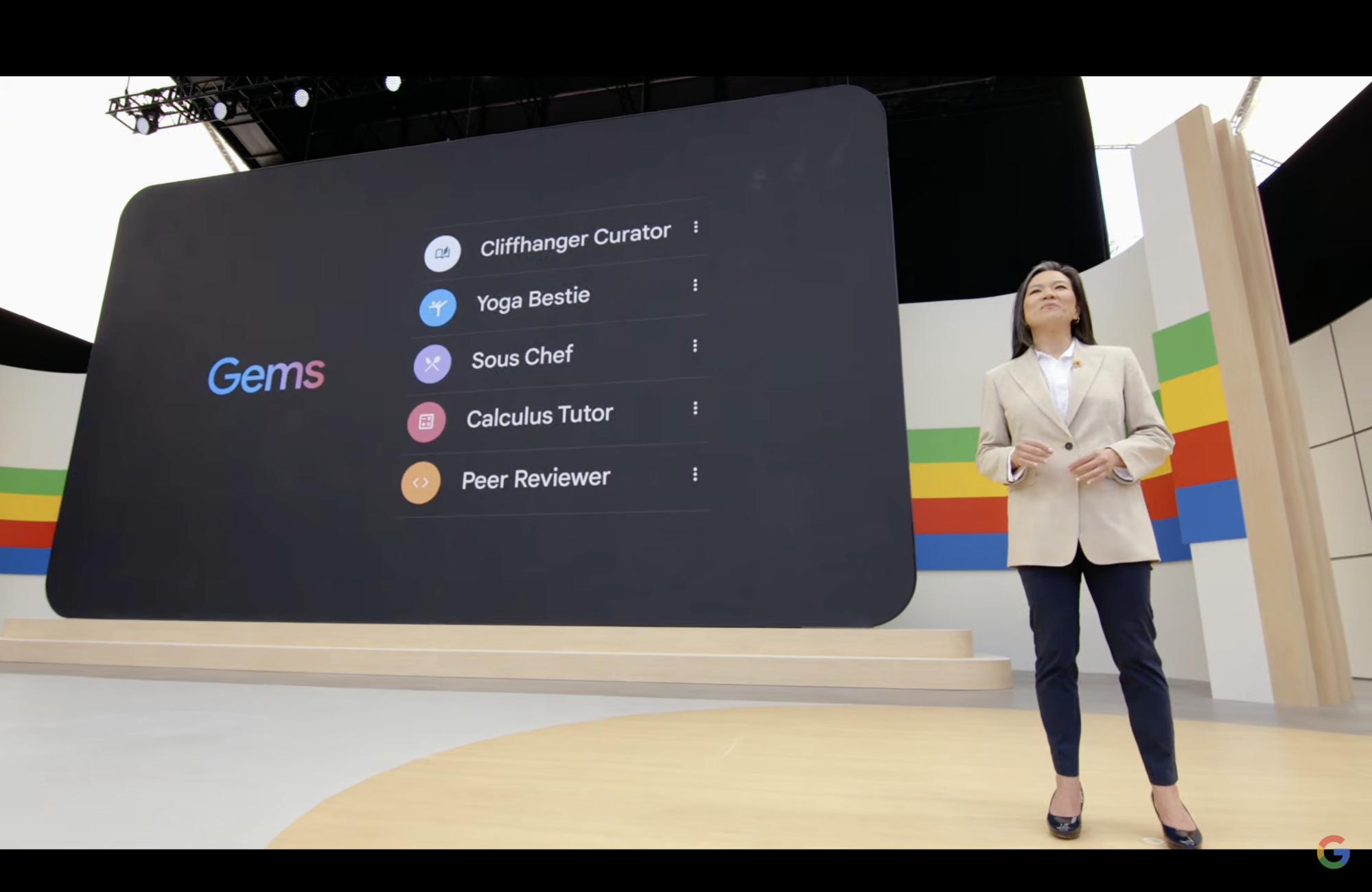 A person stands in front of a large screen that reads "gems".