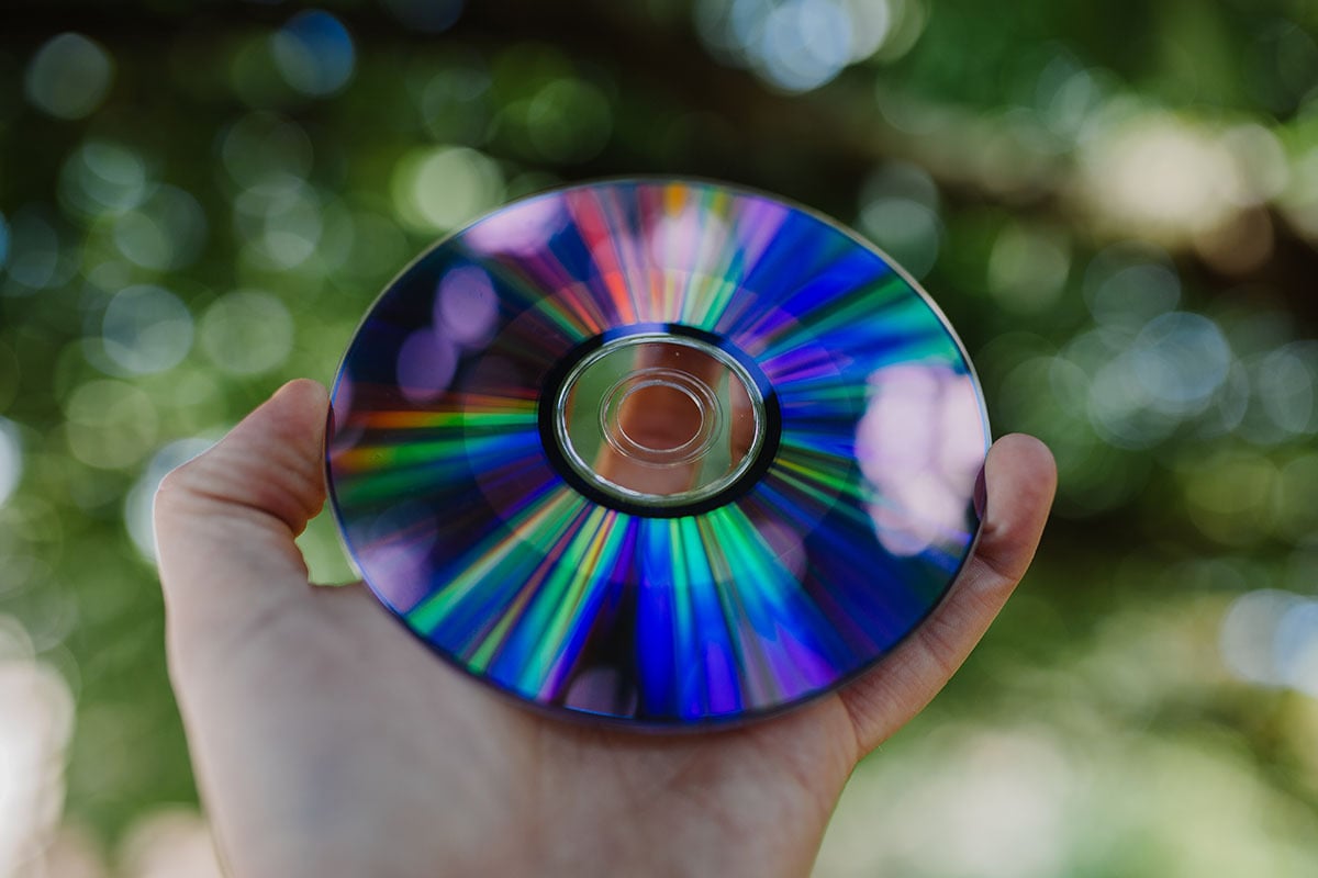 Man holding DVD outside.