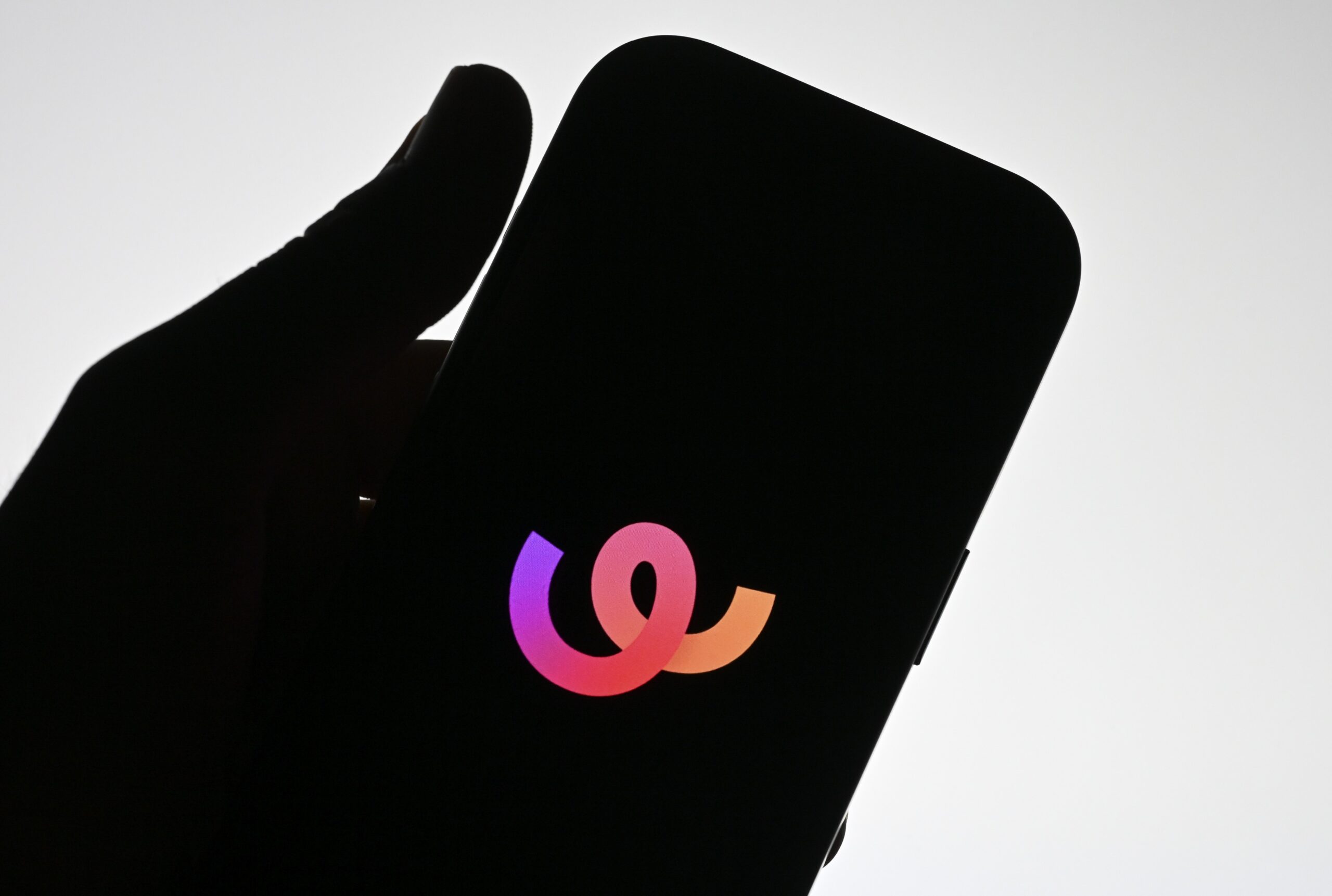 The silhouette of a hand holding a phone that displays the Whee logo.