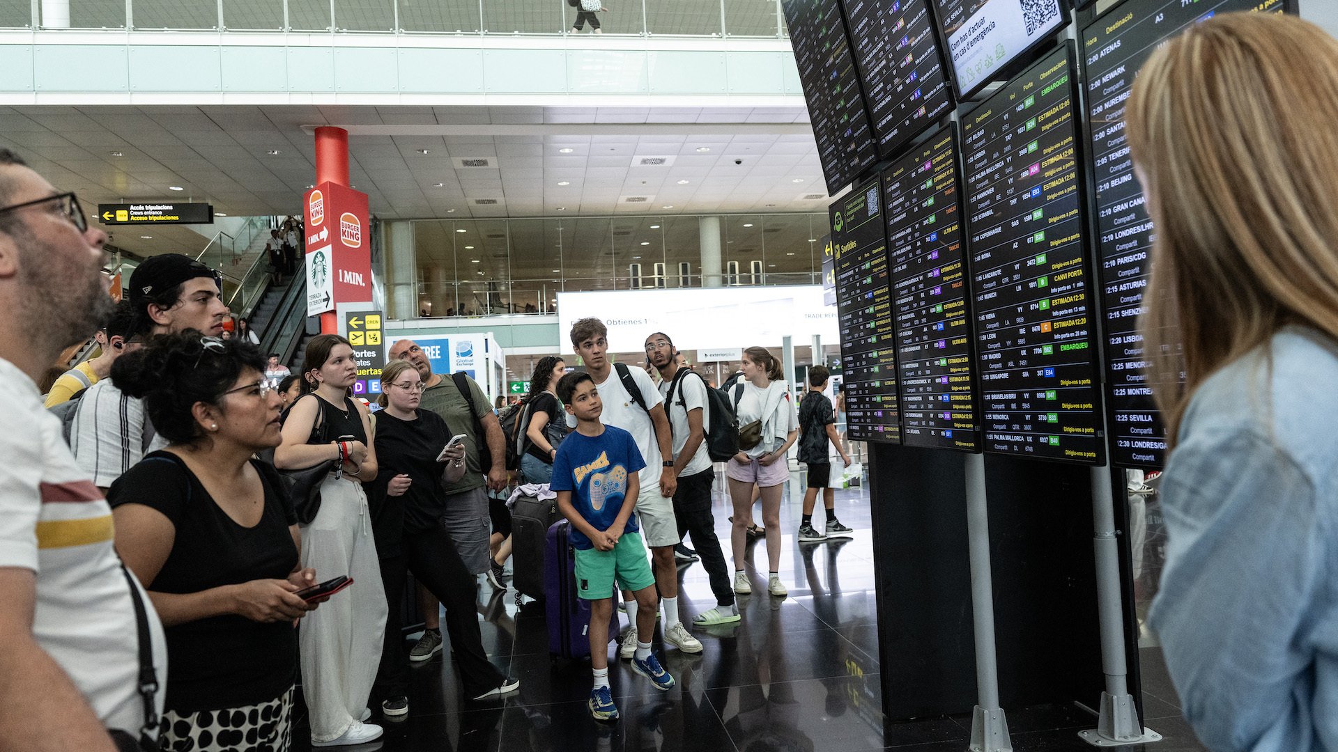 Passengers look at a screen displaying delayed flights at Barcelona Airport on July 19, 2024 in Barcelona, Spain. 