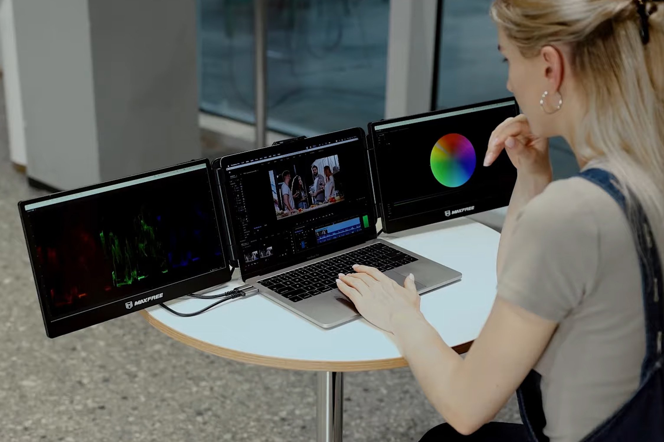 Person using laptop with three monitors