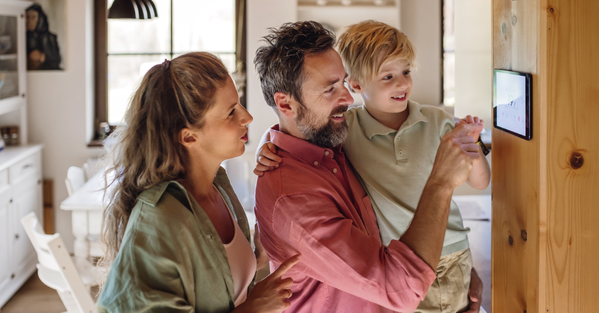 family of three looking at a smart thermostat