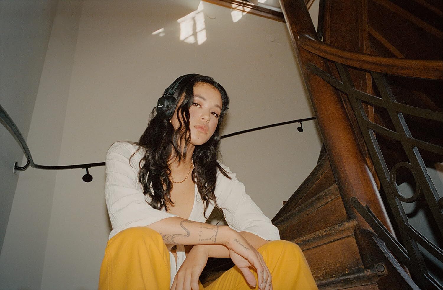 a person wearing the marshall major IV headphones sits on a set of dimly lit stairs