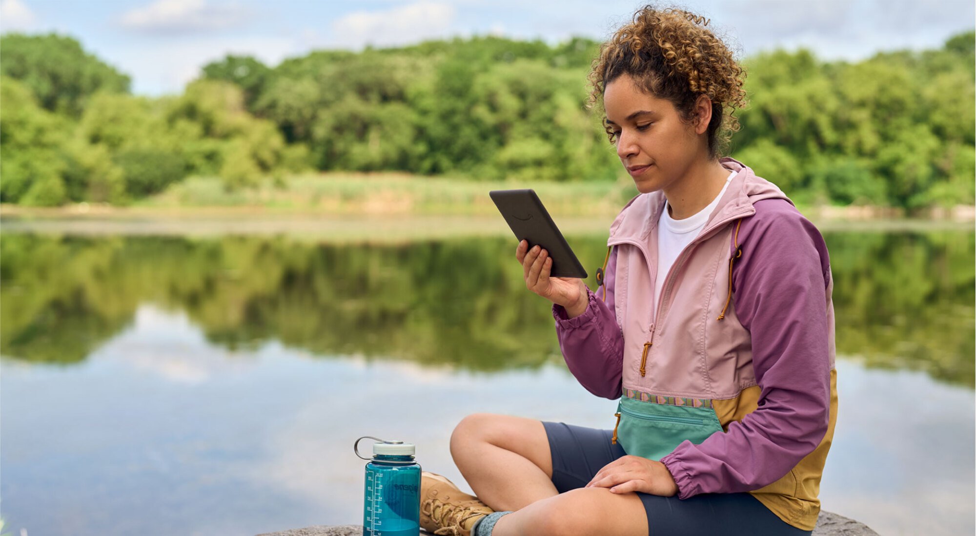 woman reading Kindle on a lake