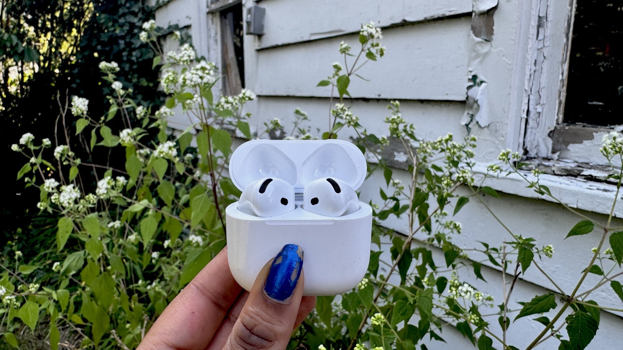 Woman holding AirPods 4 in garden