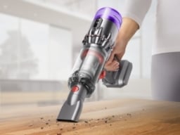 person using dyson vacuum on wood