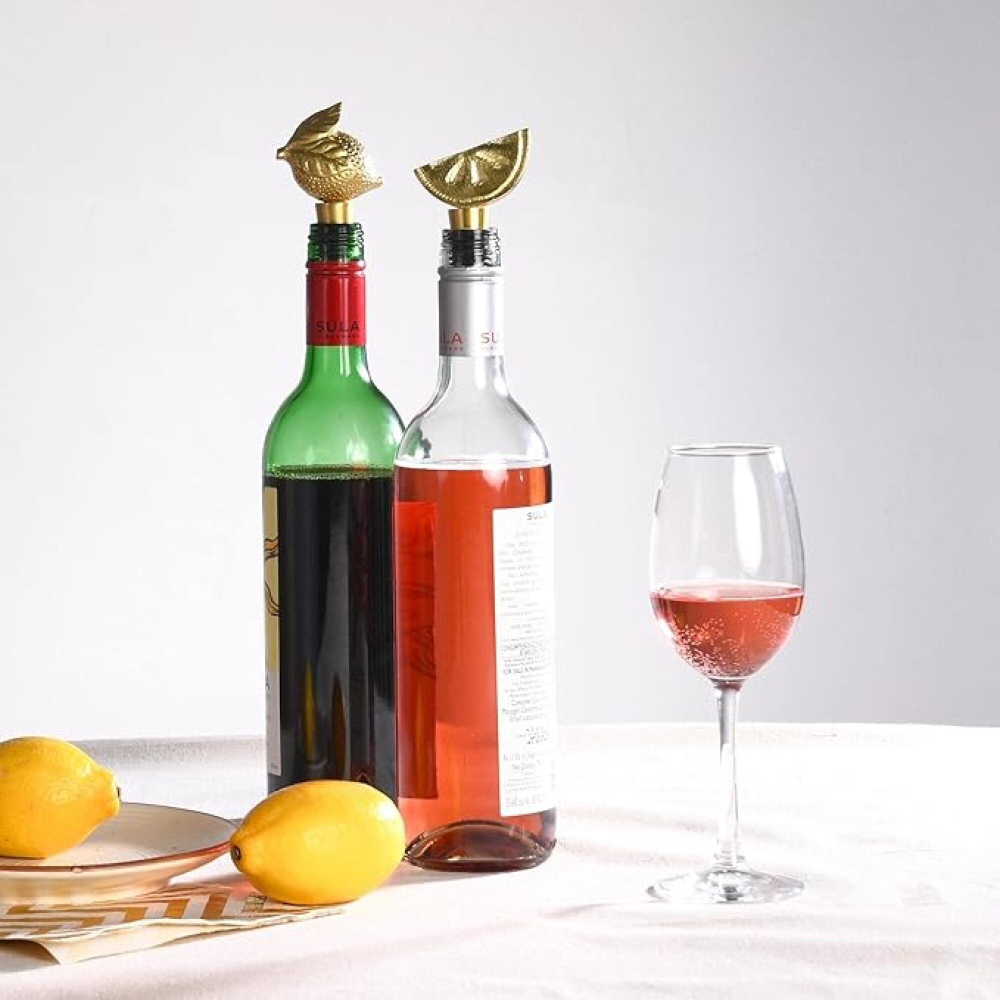 two wine bottles with stoppers, a wine glass