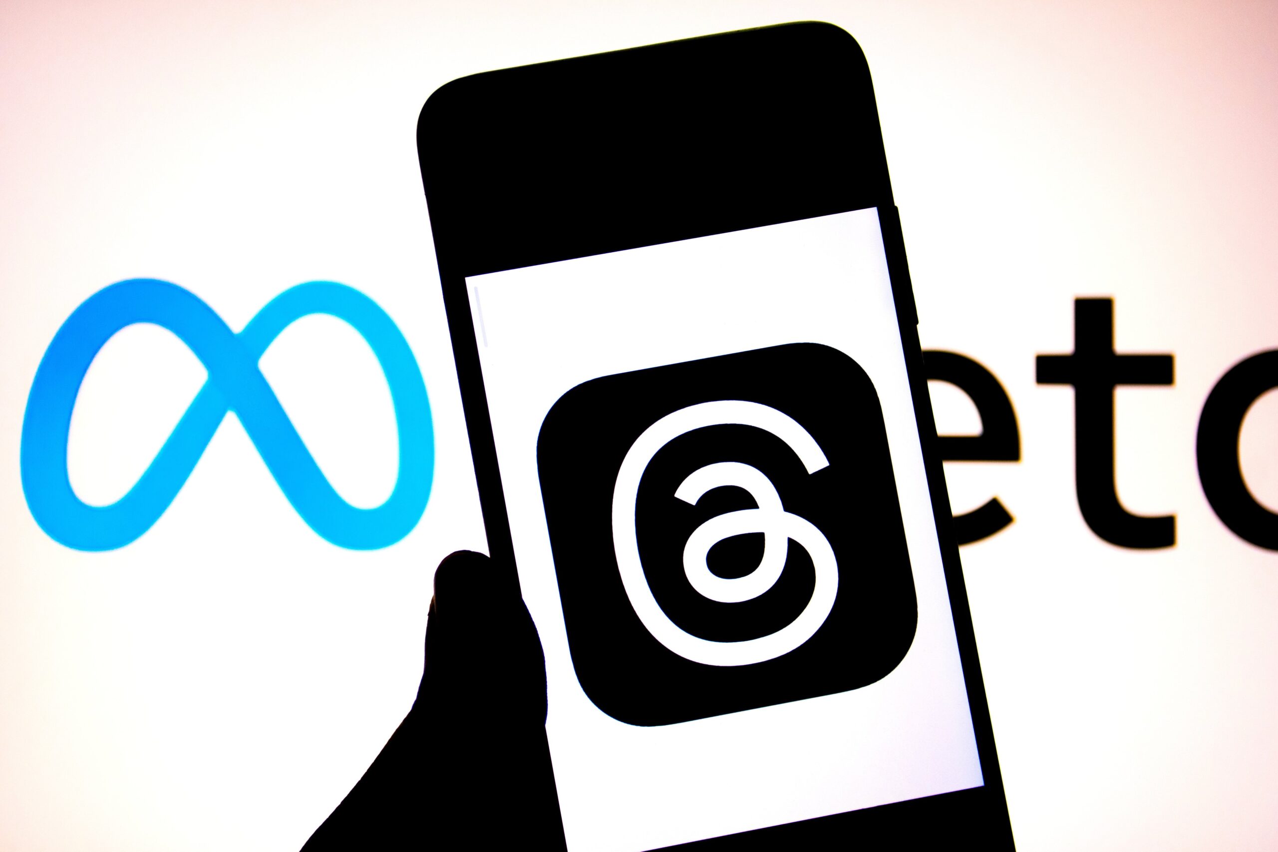 A Thread logo seen displayed on a smartphone with a Meta Logo in the background.