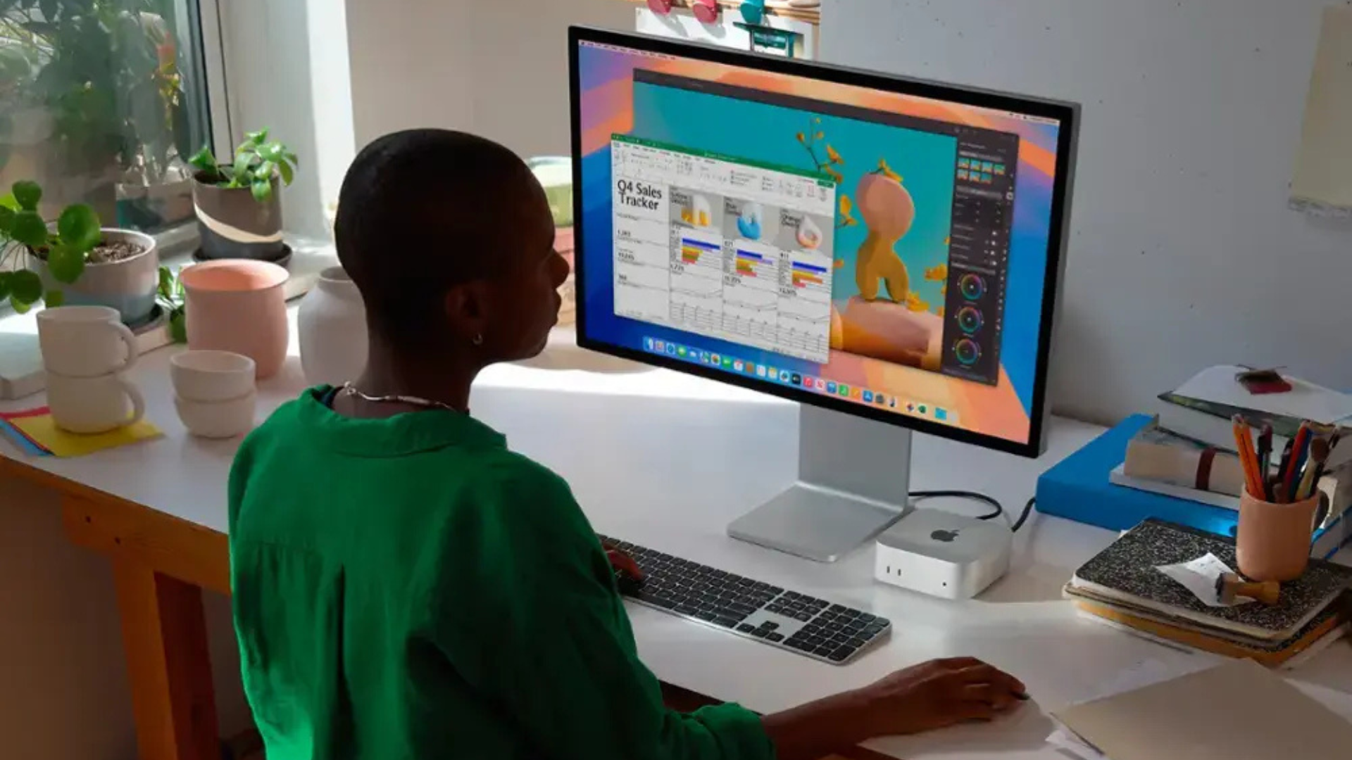 A person sitting at a desk using a Mac Mini.