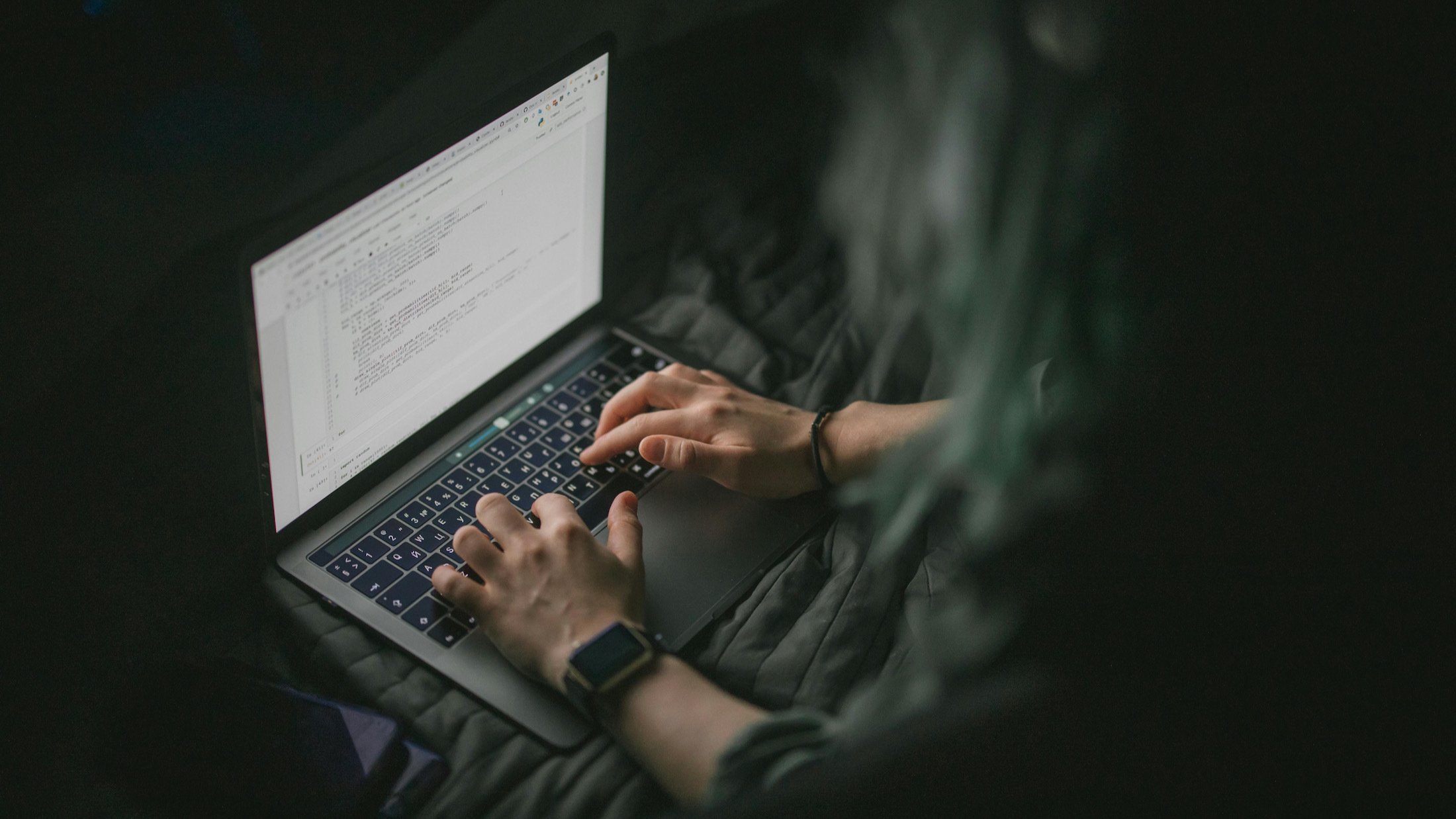 man working on laptop screen in dark room