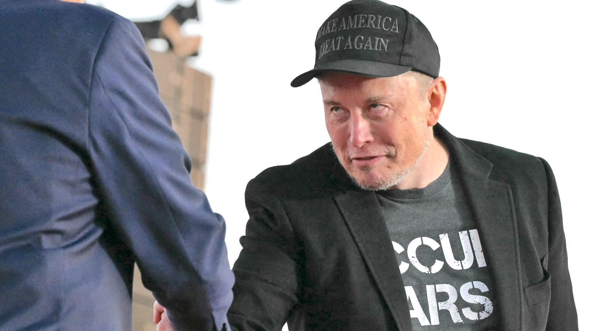 Elon Musk, with a strange servile look, shakes hands with Donald Trump.