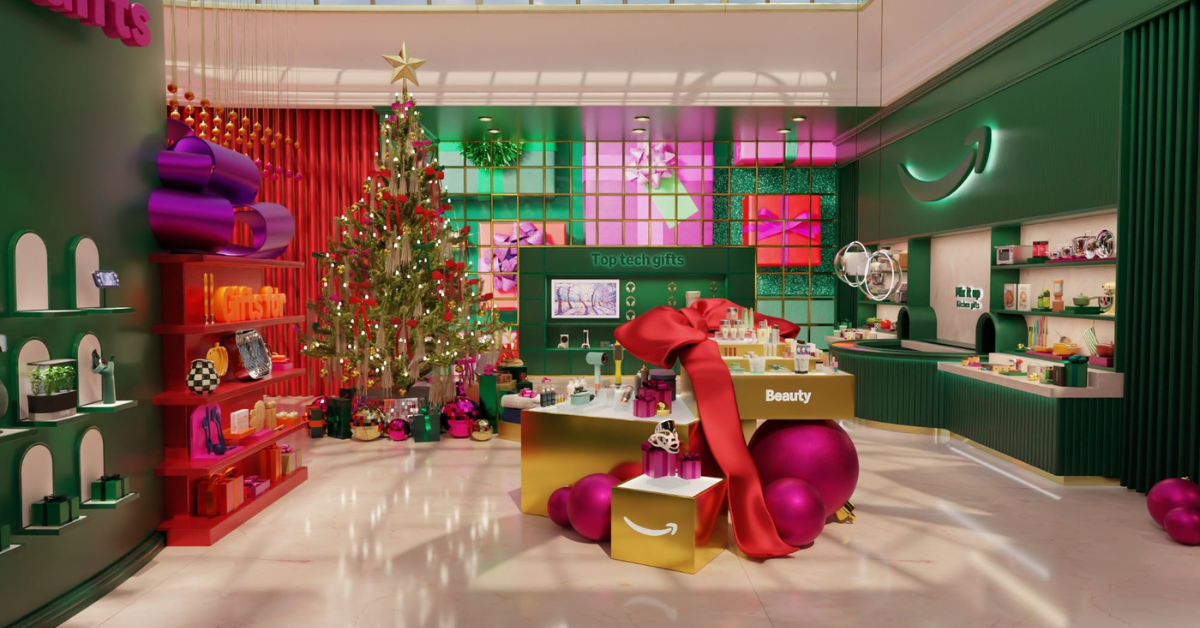 A festive virtual storefront with a Christmas tree, wrapped gifts, and displays of various products including beauty items and tech gadgets. The Amazon logo is visible in the background.