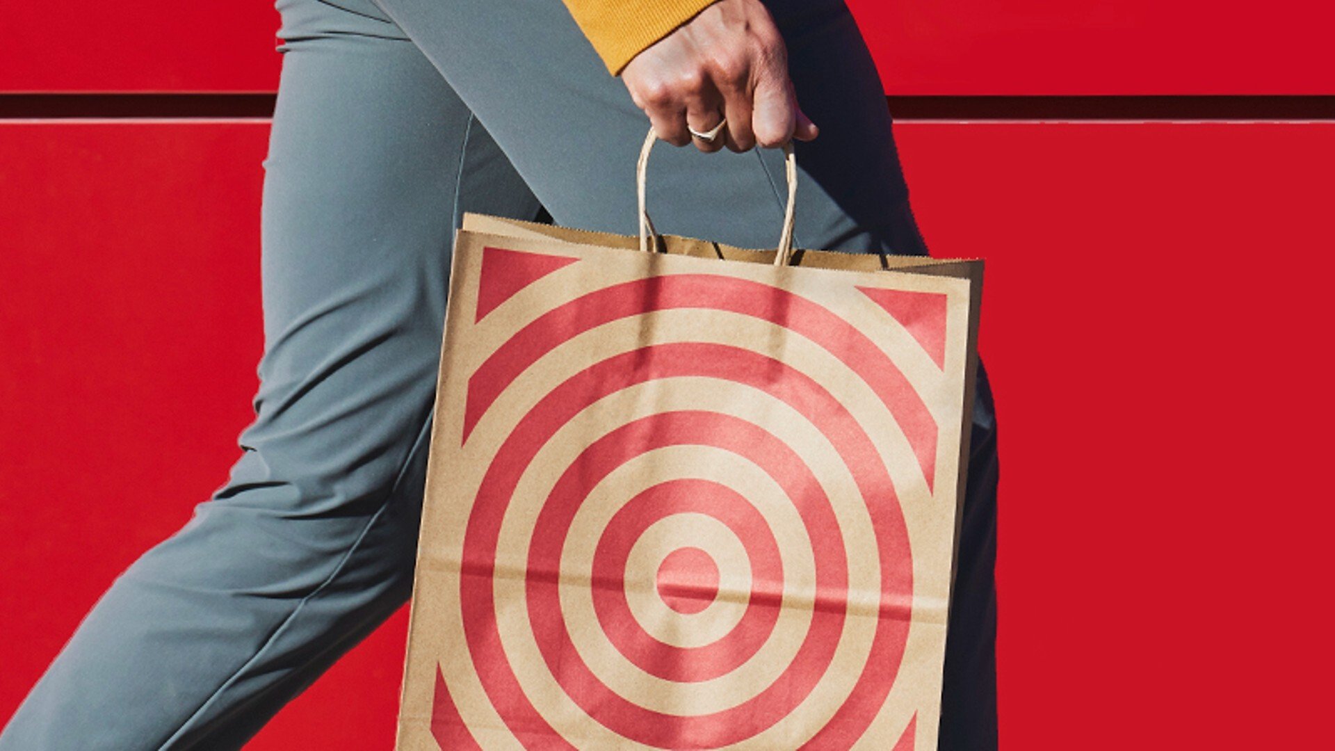 a person holding a brown paper target bag with the red target image on the front