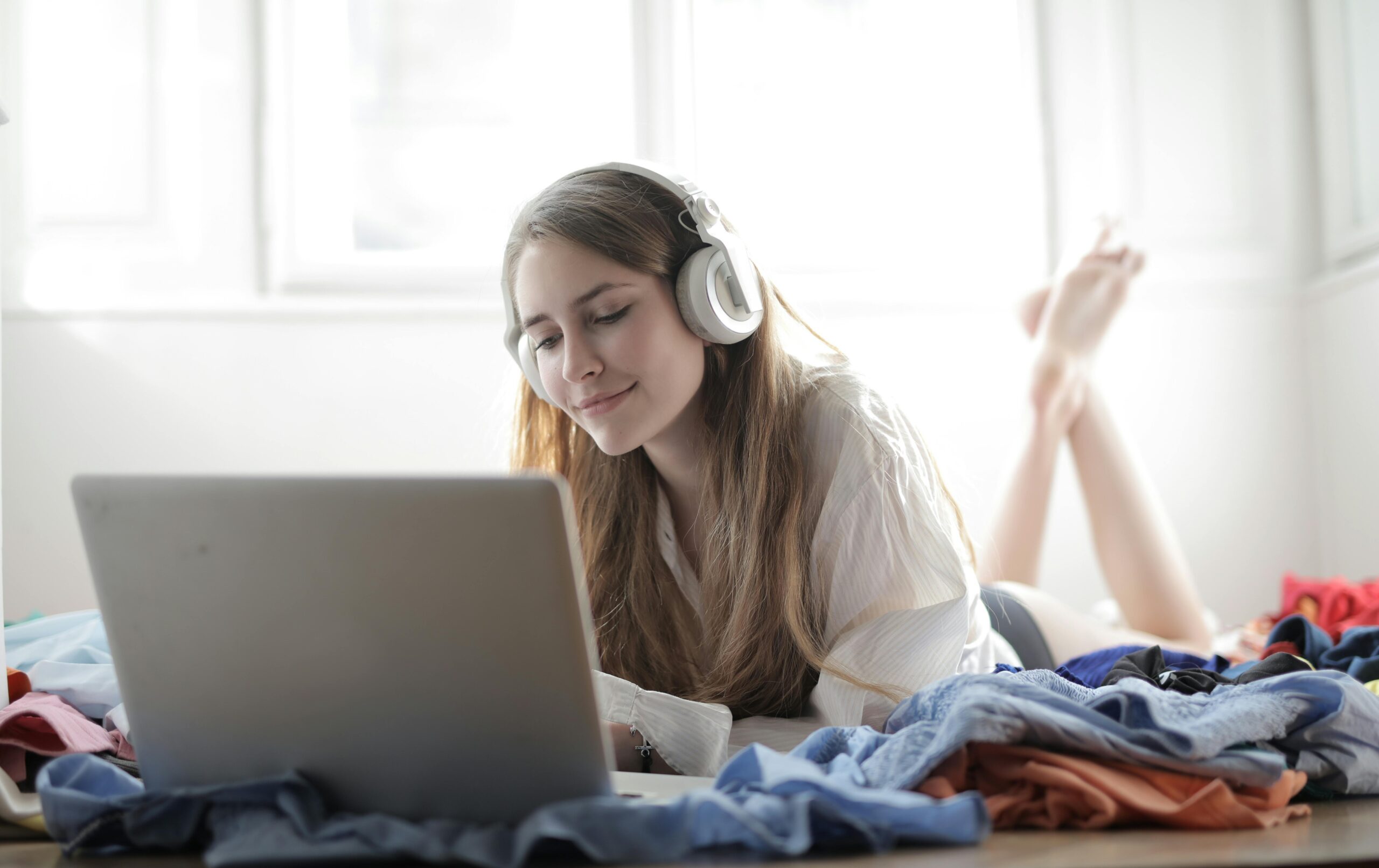 young woman wearing headphones and watching content on laptop