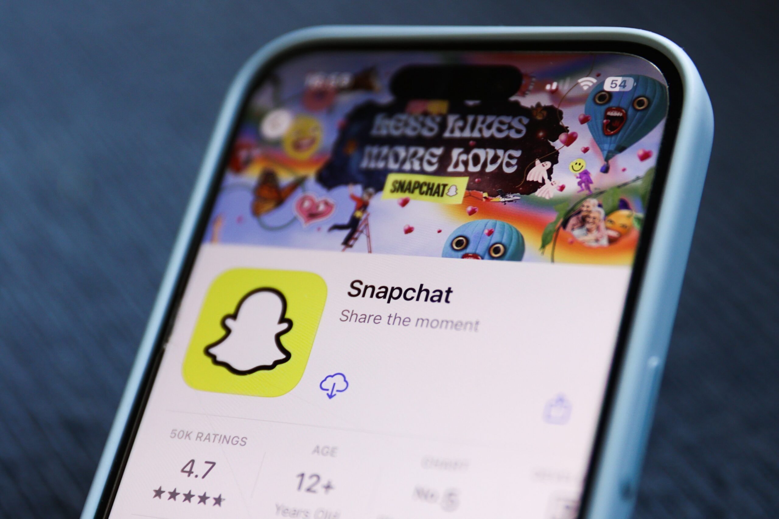 A phone shows the Snapchat listing in the Apple App Store.