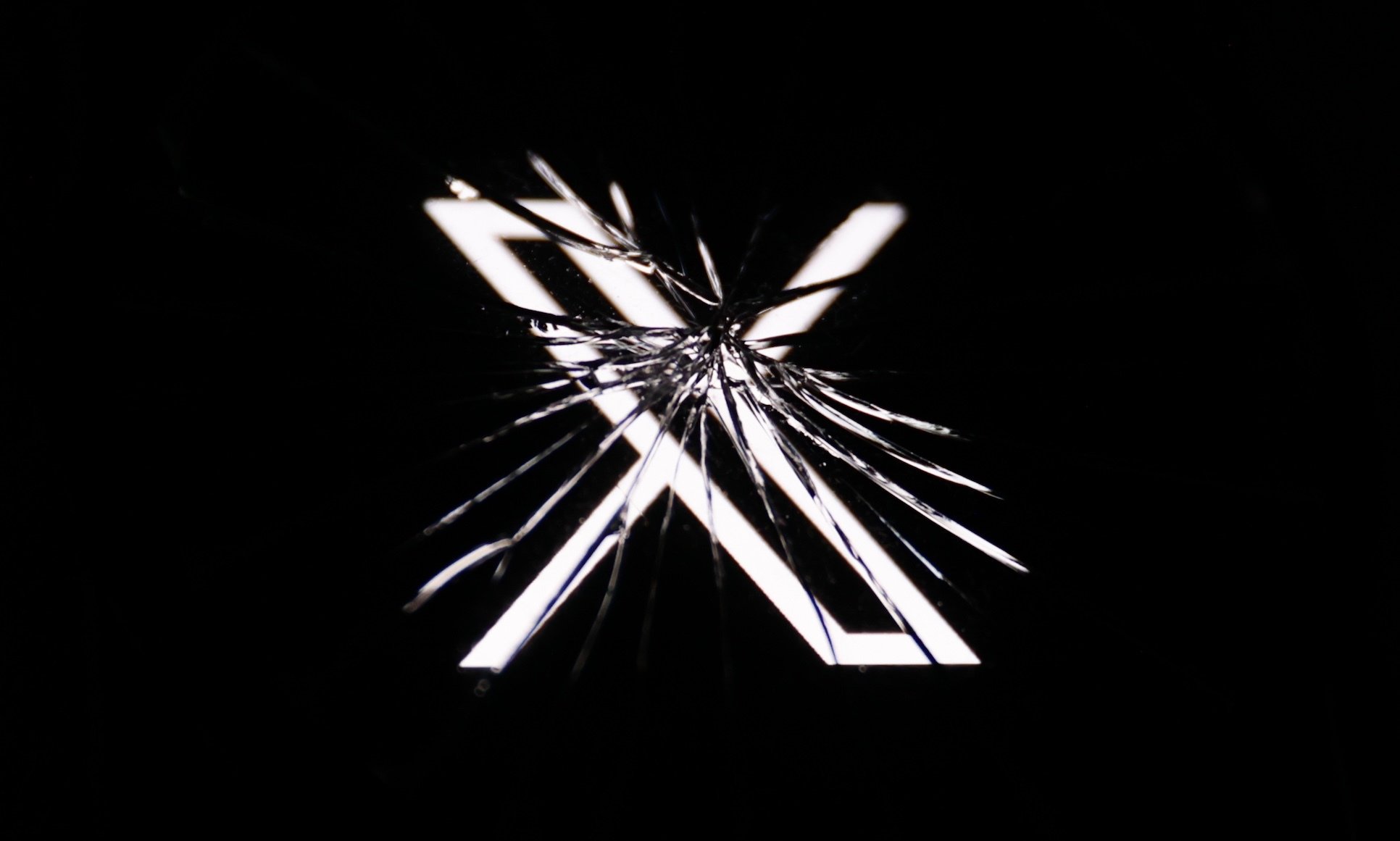 An X logo seen through shattered glass.