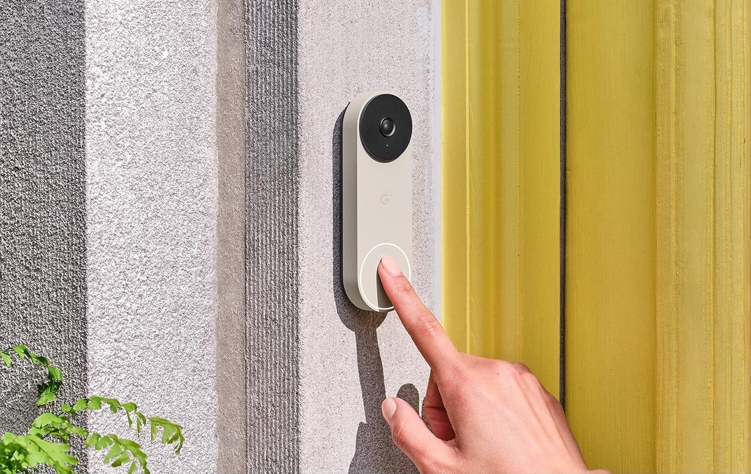 a person's right index finger approaches touching the google nest video doorbell that's affixed next to a home's front door
