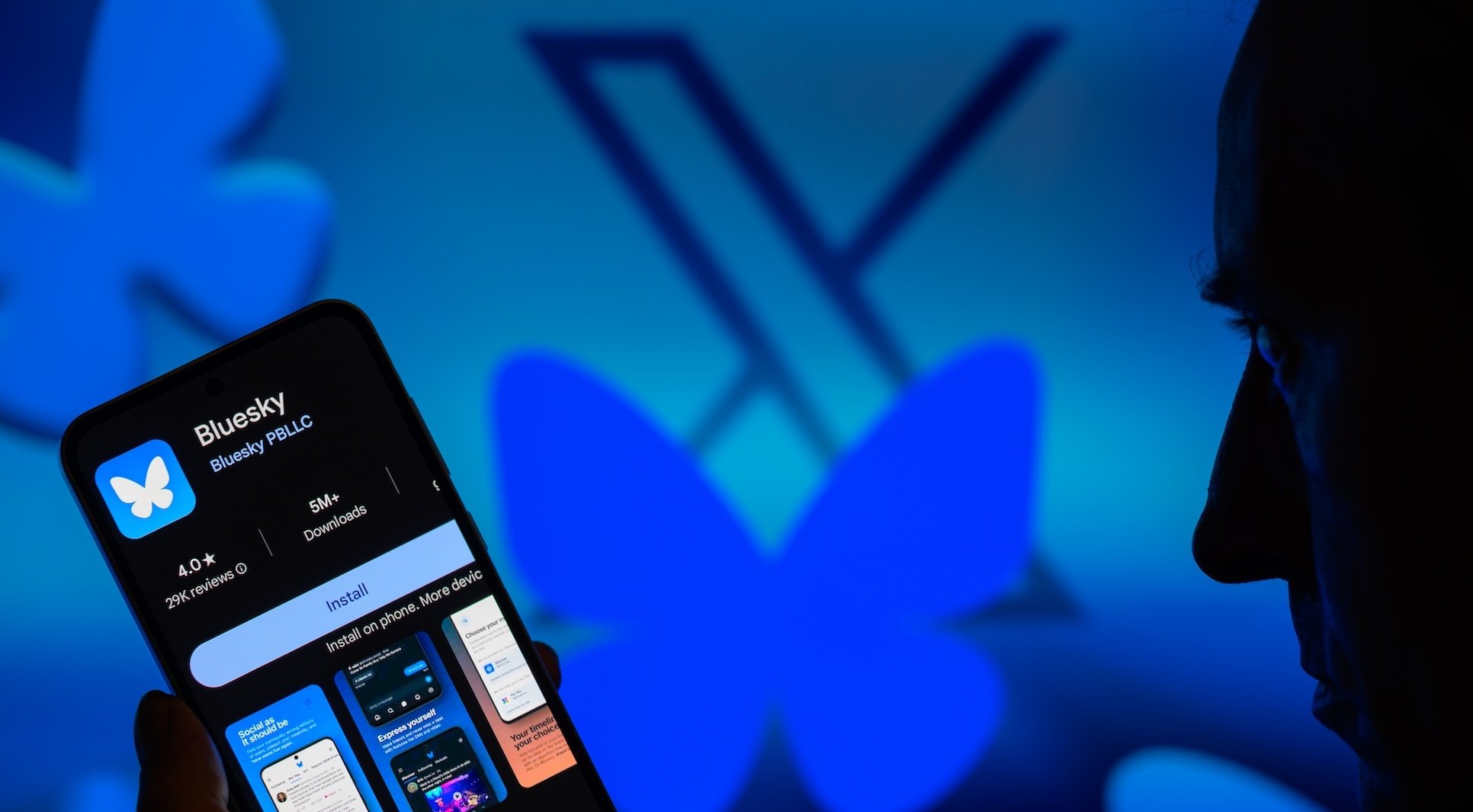 Bluesky's butterfly logo covers an X while a man looks at the Bluesky app on his phone