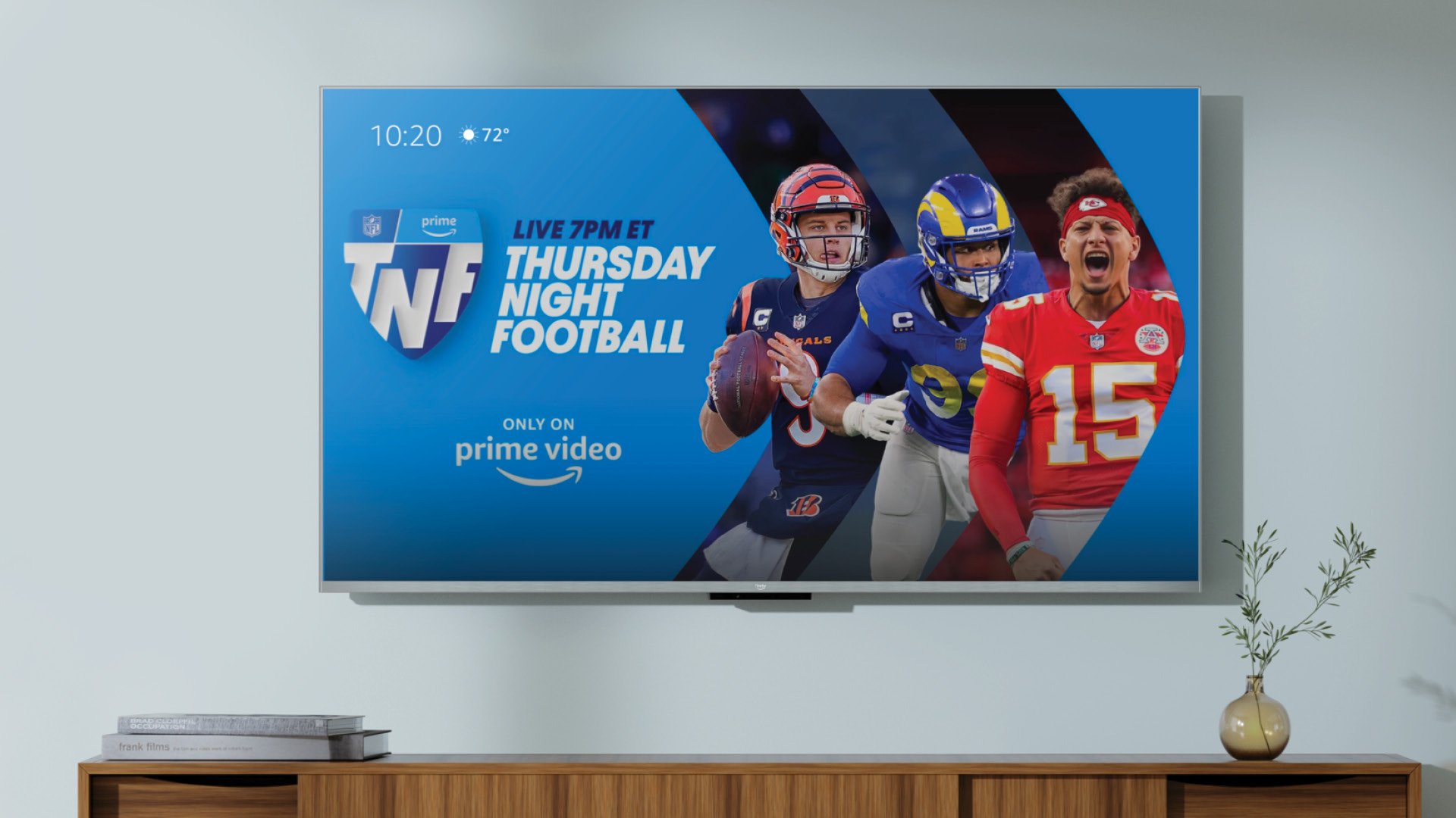 Amazon Fire TV hanging on wall above TV stand with football players and Prime logo on screen