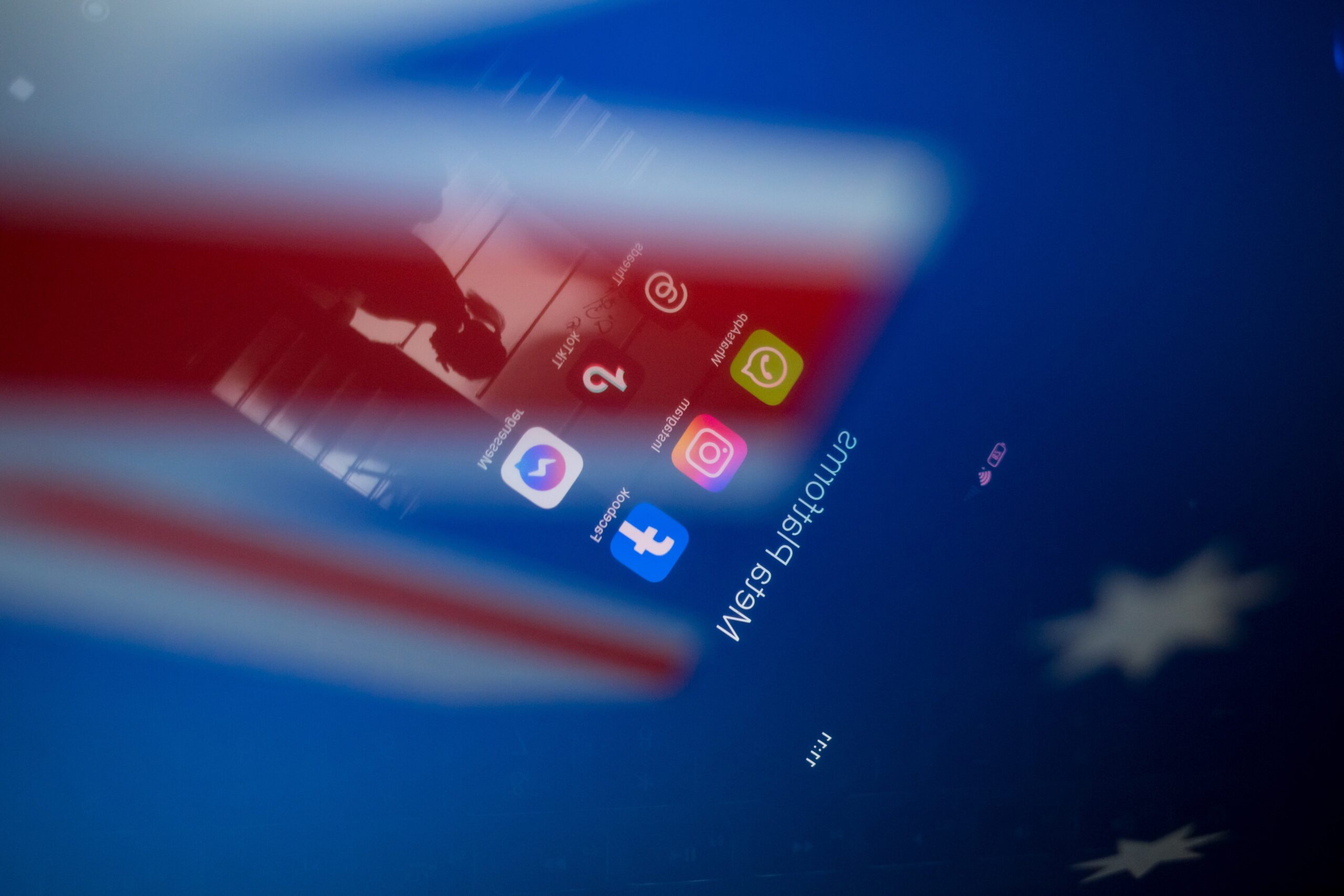 Social network logos display on a smartphone screen and the Australian flag appears on a computer screen in this photo illustration in Athens, Greece, on November 21, 2024. The Australian government proposes a ban on social media for all citizens under 16. Citing the success of recently introduced restrictions on mobile phones in Australian schools, the prime minister announces the ban by declaring that it is doing harm to children and he is calling time on it.