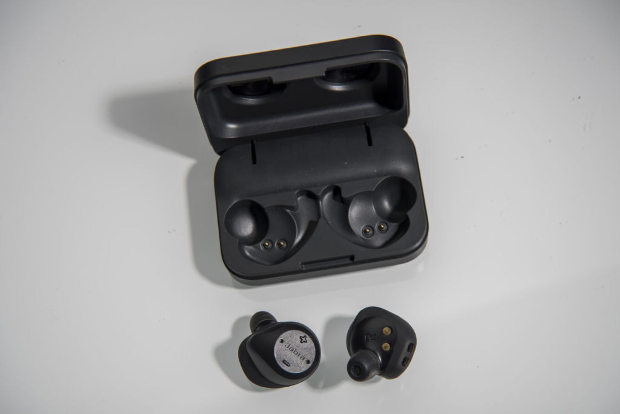 Close up of Jabra Elite Sport earbuds next to their charging case