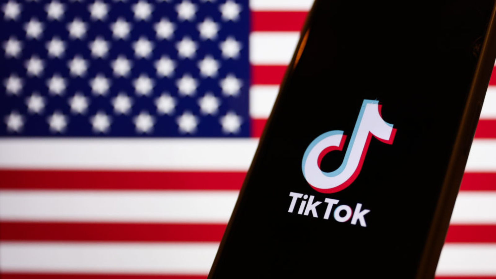 American flag displayed on a laptop screen and TikTok logo displayed on a phone screen.