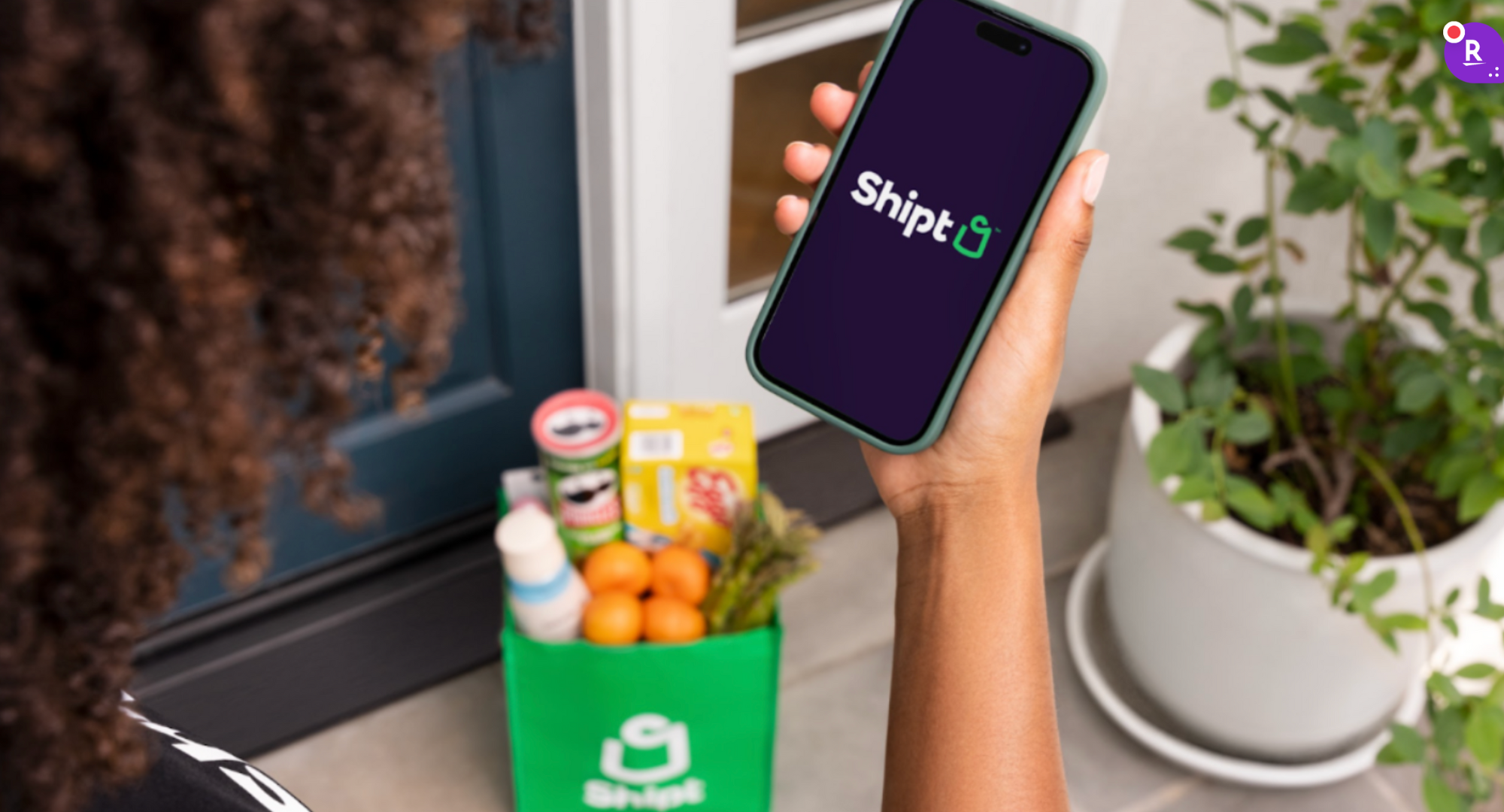 Person holding a smartphone with the Shipt logo 