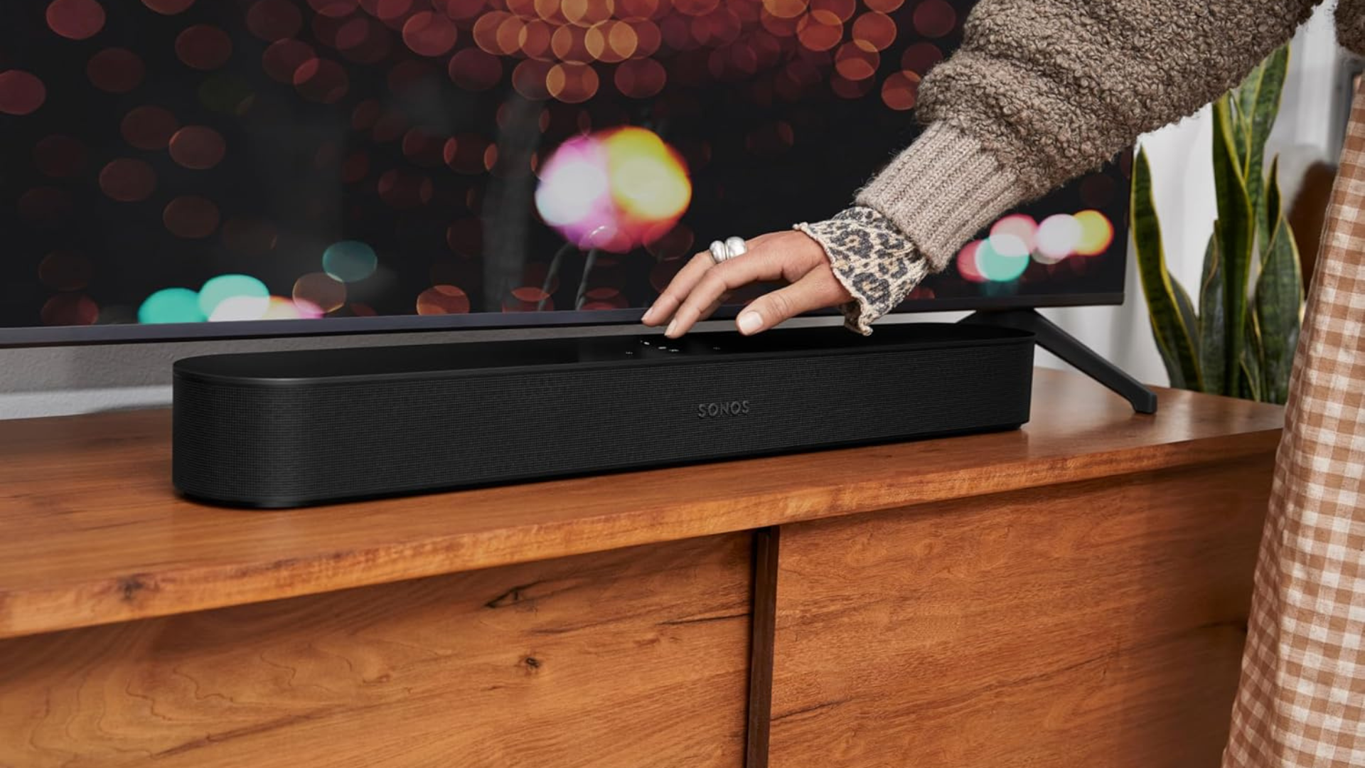 A person touching the top of a Sonos soundbar.