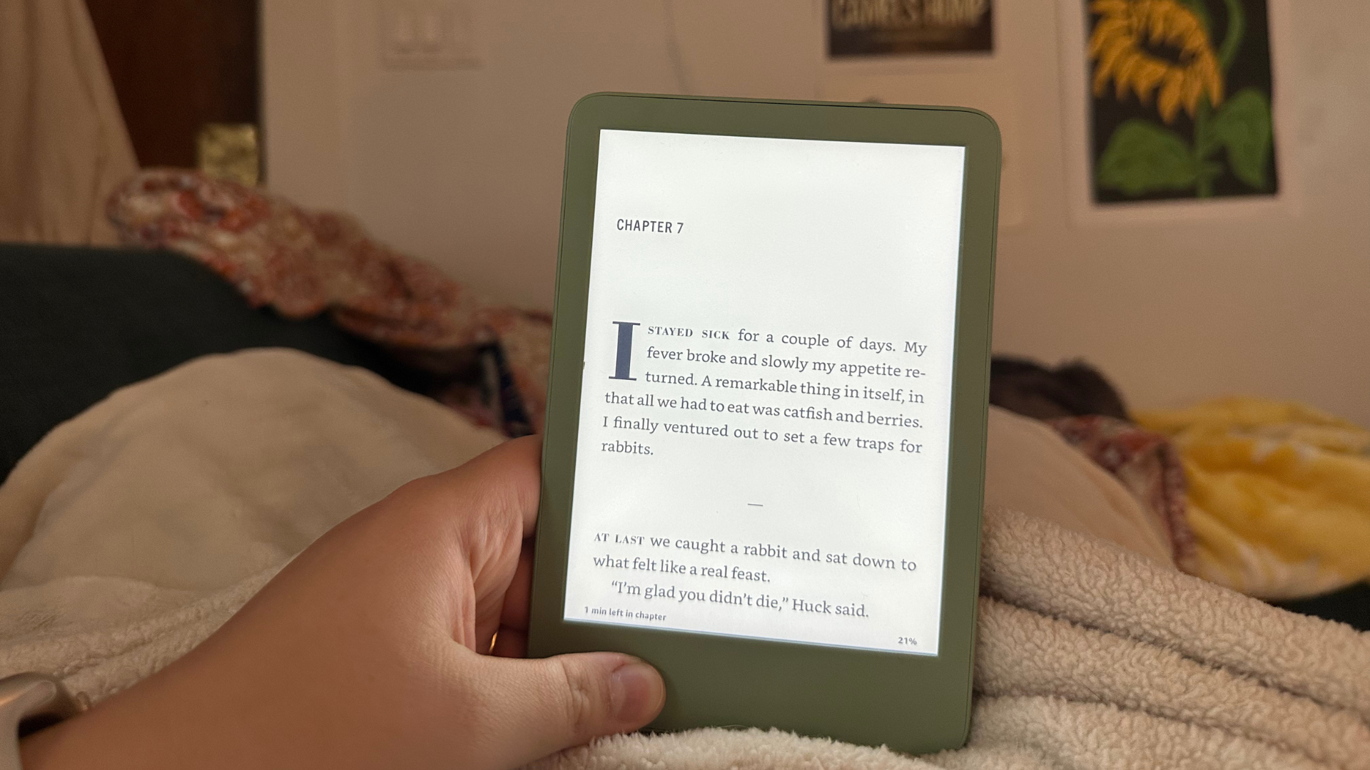 A hand holding a Kindle against a blanket