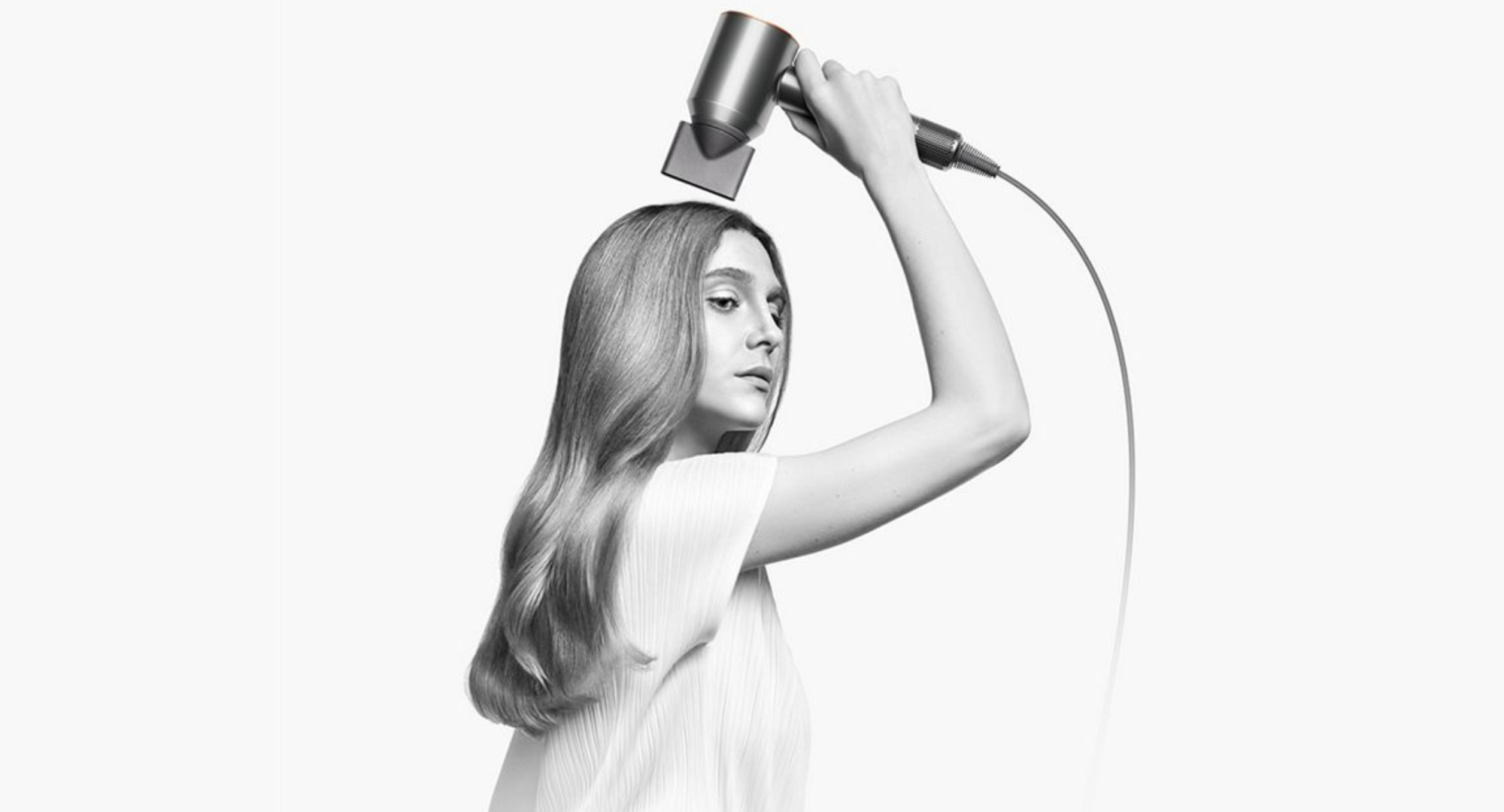 black and white photo of a woman using the dyson supersonic origin hairdryer 