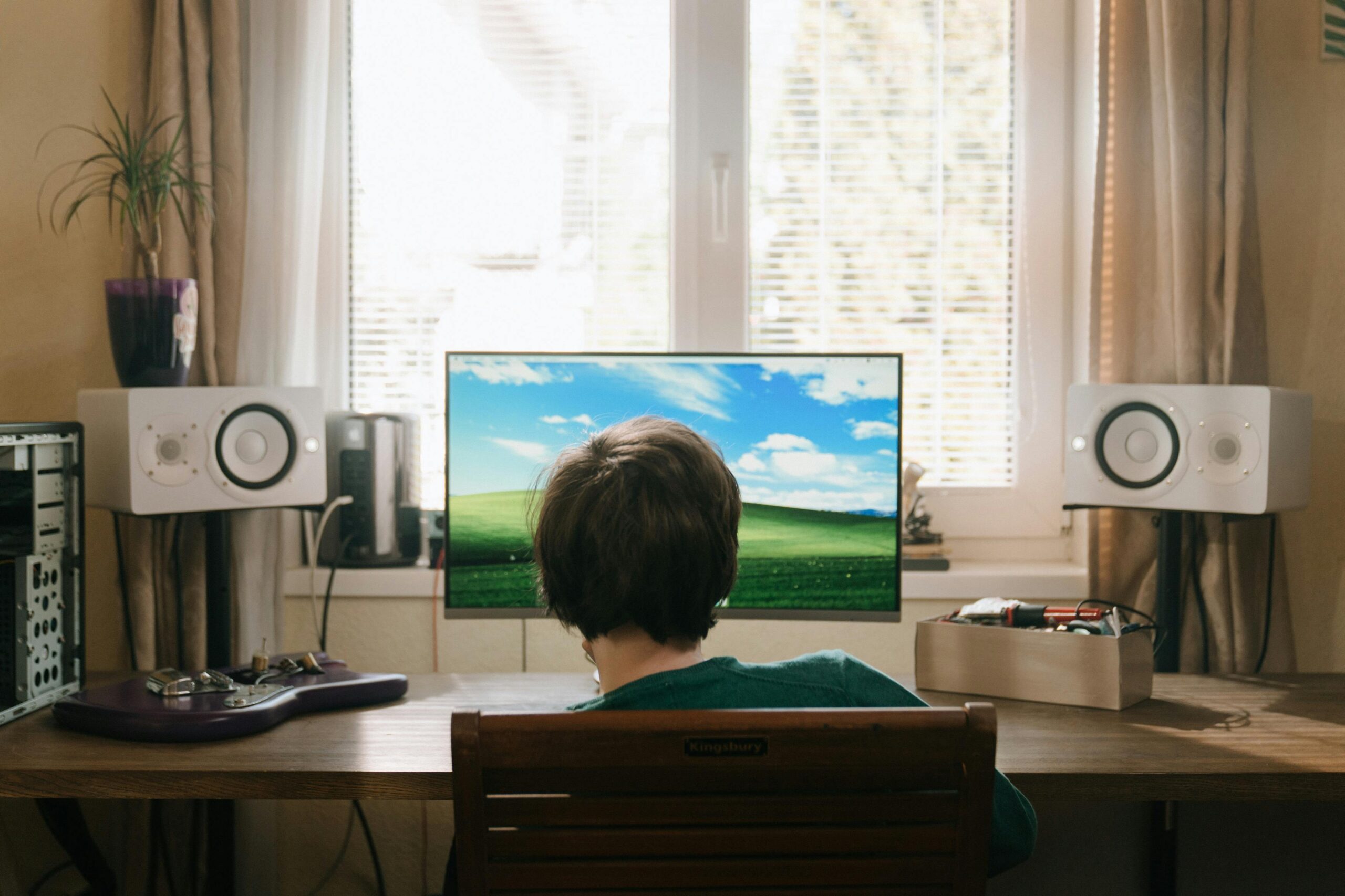 man sitting in front of windows desktop computer with dual speakers