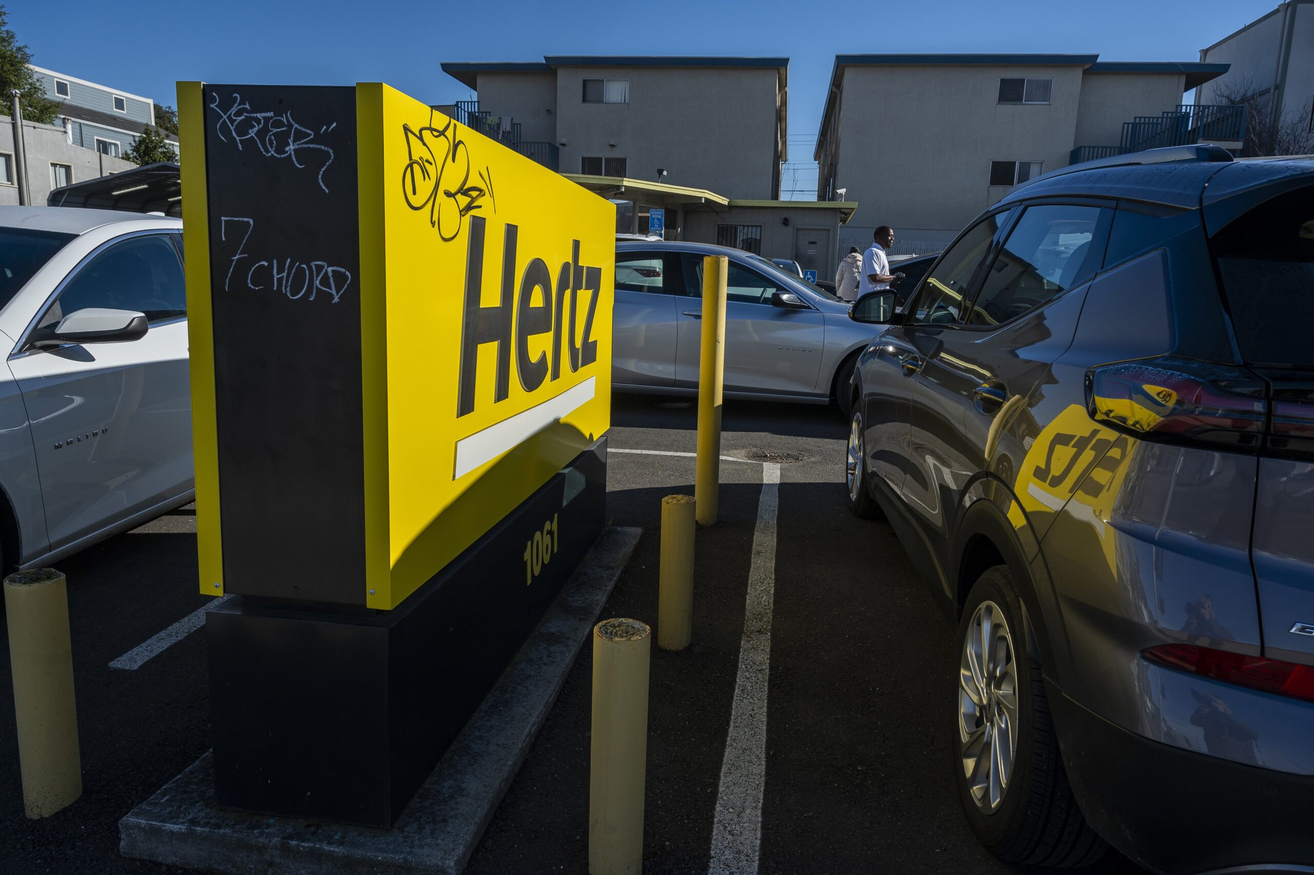 a hertz sign in between two parked cars