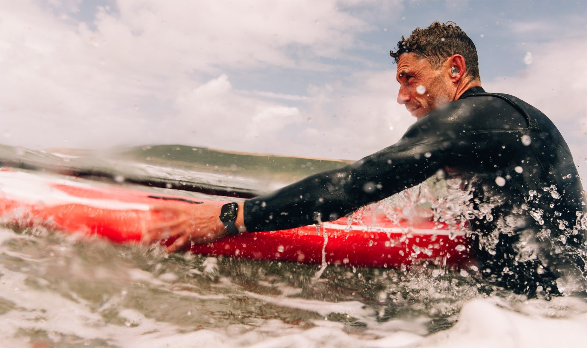 man on surfboard in ocean wearing apple watch