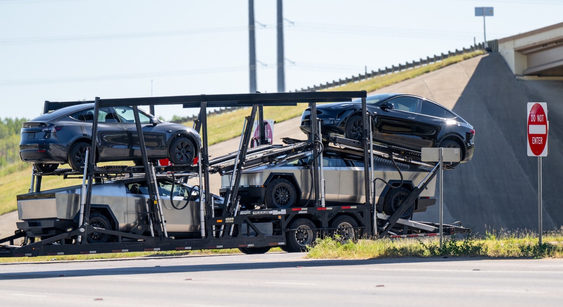 Tesla vehicles, including Cybertrucks, loaded on a transport that seems to be going nowhere.