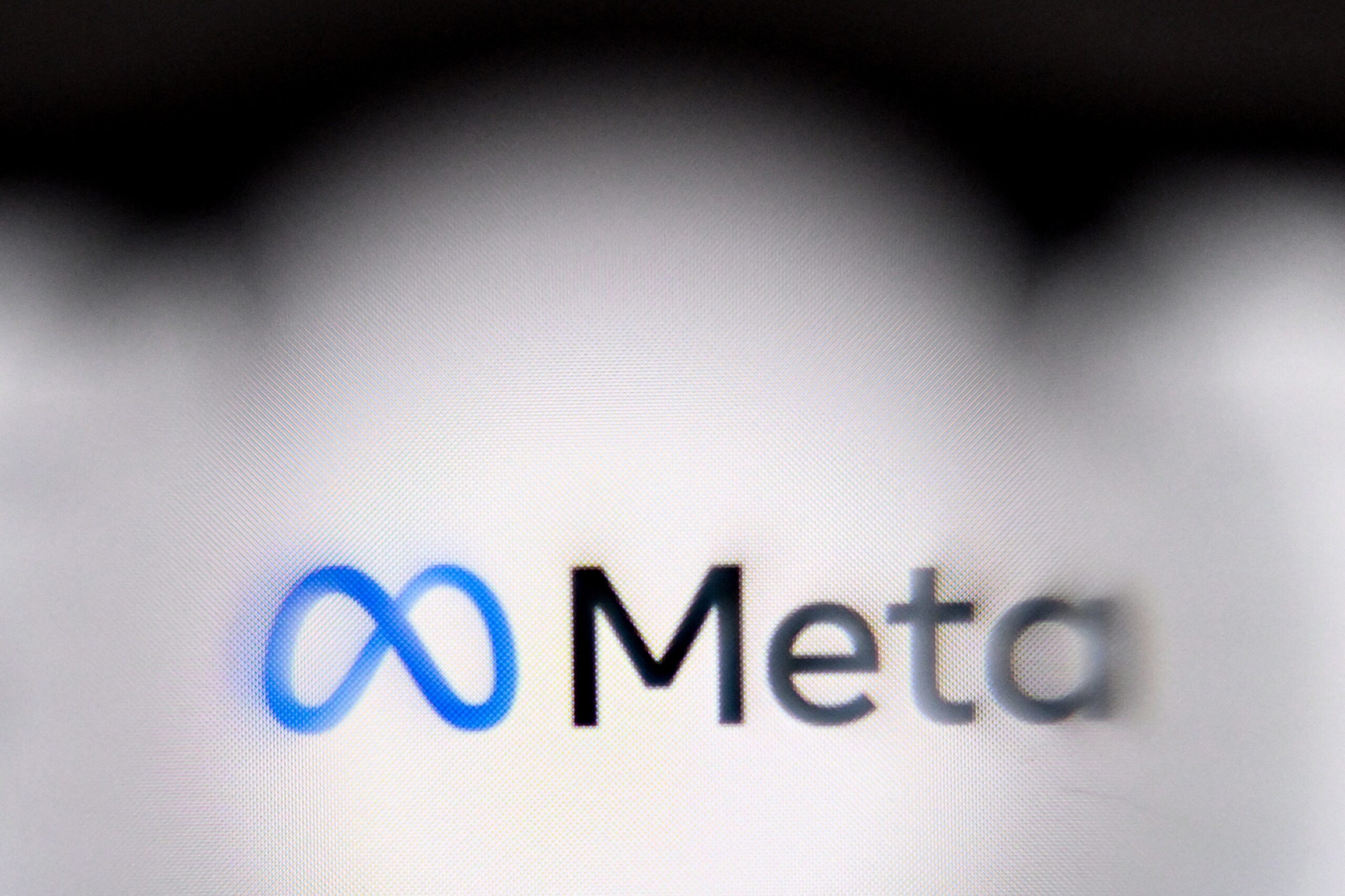 The Meta logo on a blurred computer screen.