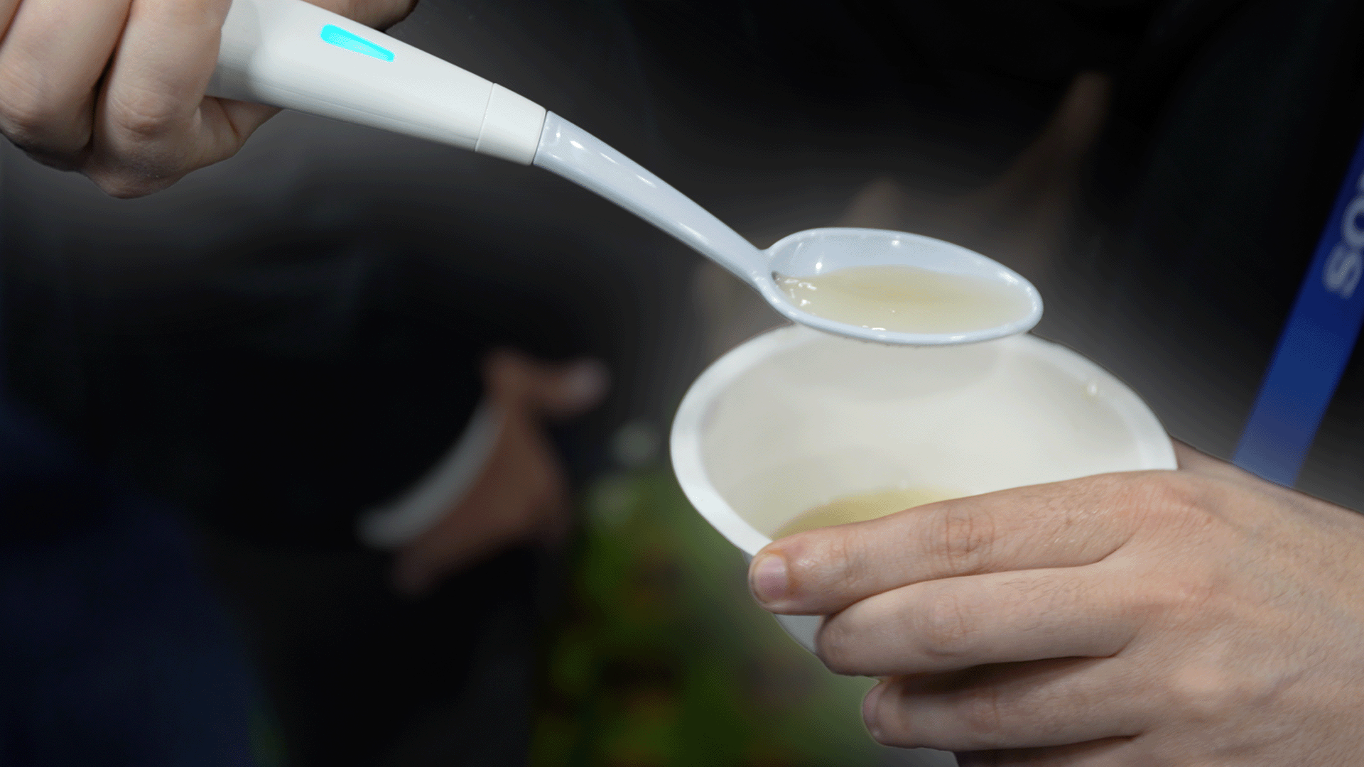 A plastic spoon filled with soup.