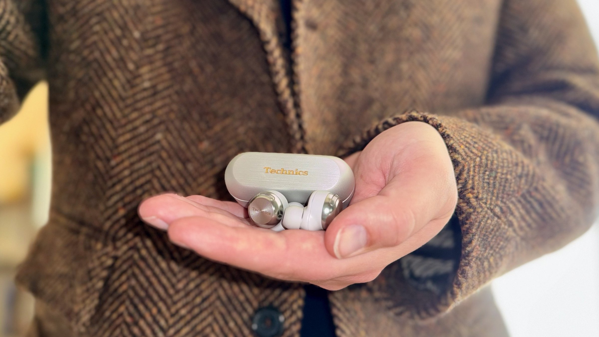 close-up of man holding panasonic technics az100 wireless earbuds with silver charging case