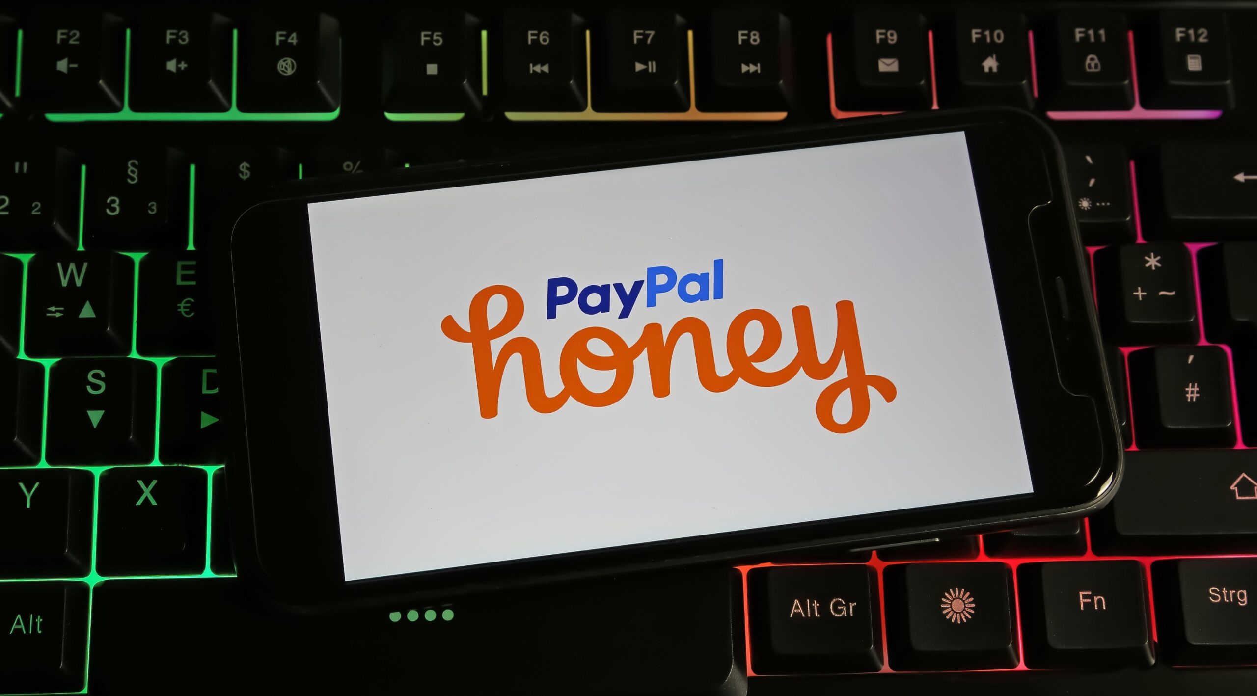 Closeup of smartphone on pc keyboard with logo lettering of Paypal Honey