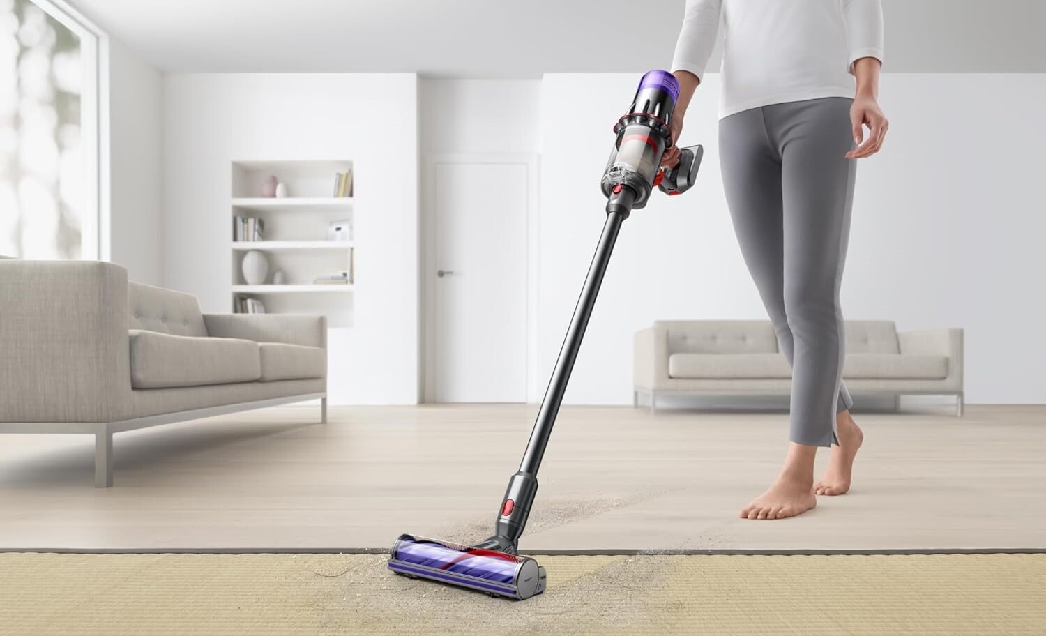 a person uses the dyson digital slim cordless vacuum on carpet in a living room