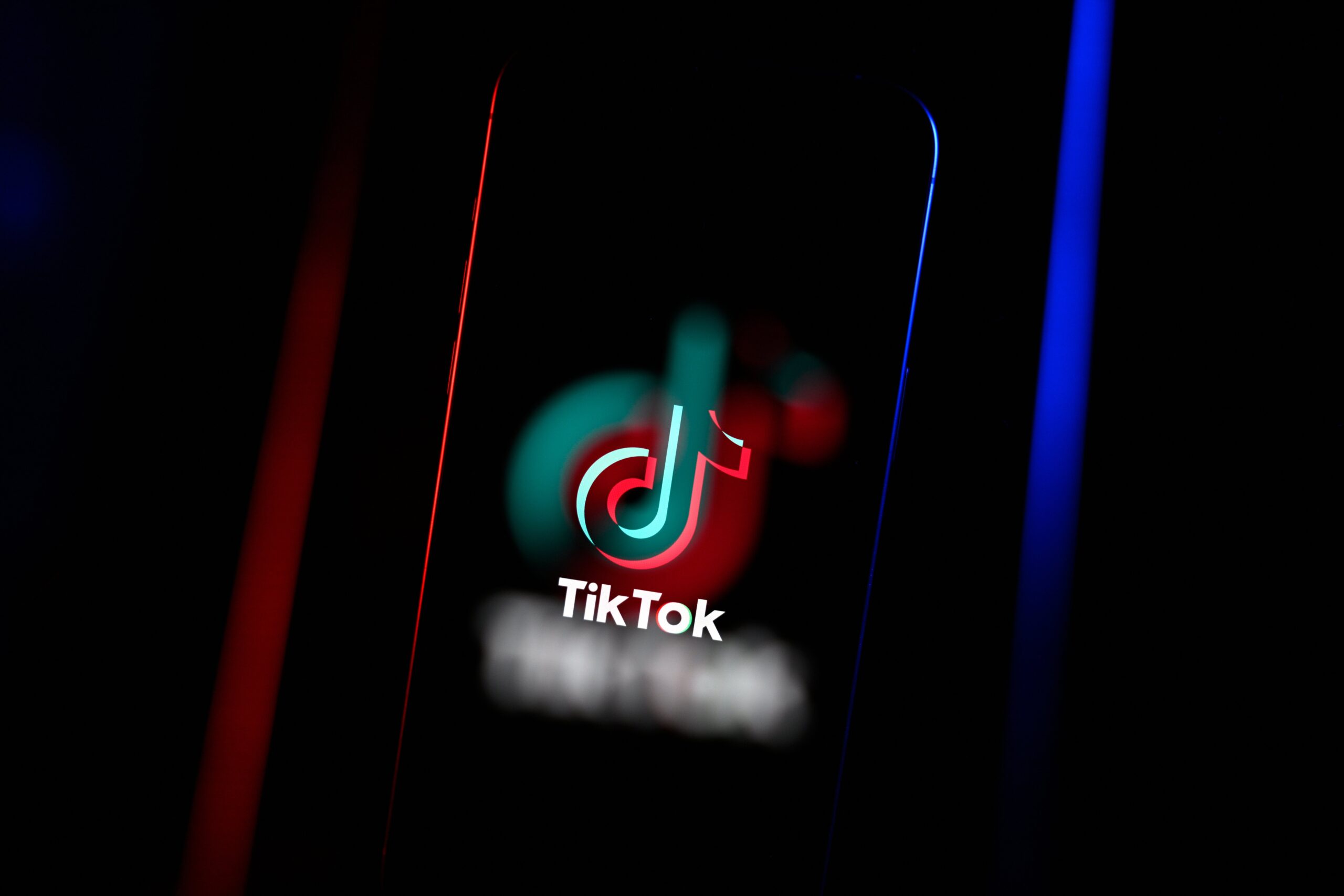 A blurry phone screen displaying the TikTok logo. 